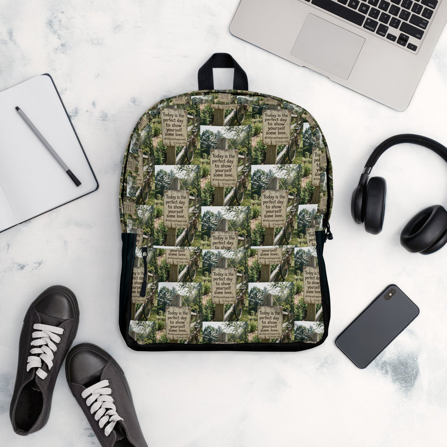 Green quote collage backpack with black bottom, front pocket, and zip-top opening.
