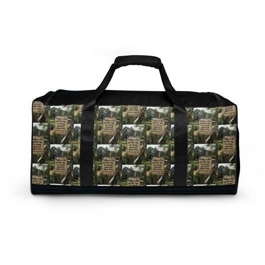 Black duffle bag with green-and-cream text pattern panel, top handle, wide strap