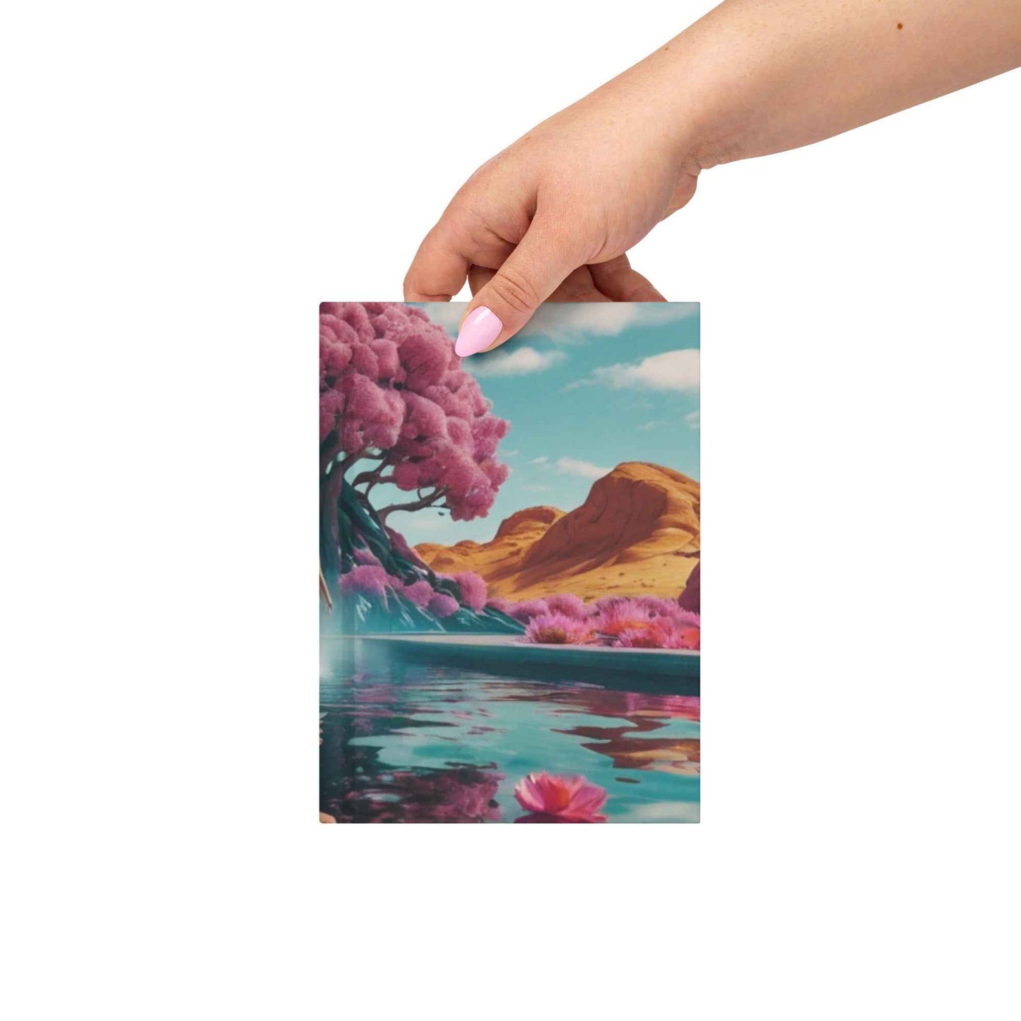 Matte hardcover journal held in hand with landscape cover art and magenta flowers