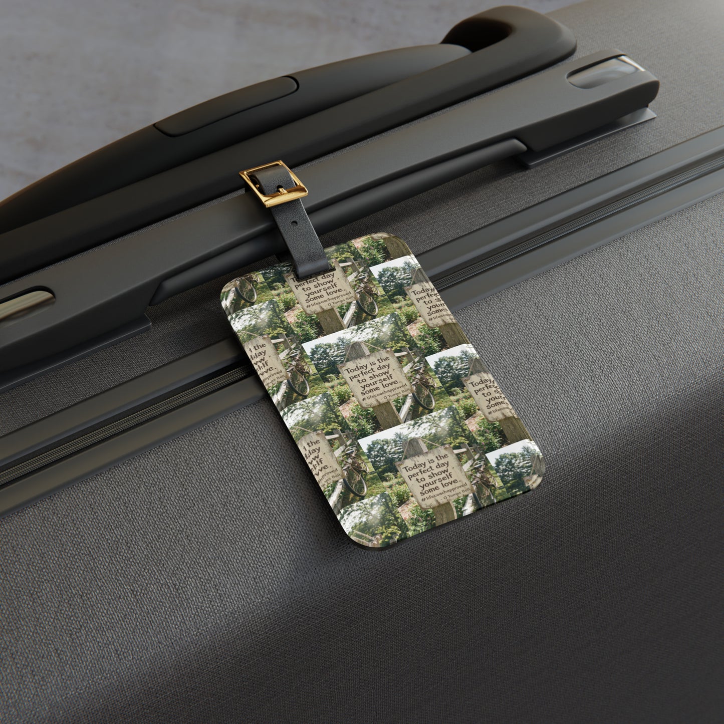 Dark luggage tag with quote-and-nature print, attached with metal clip to suitcase