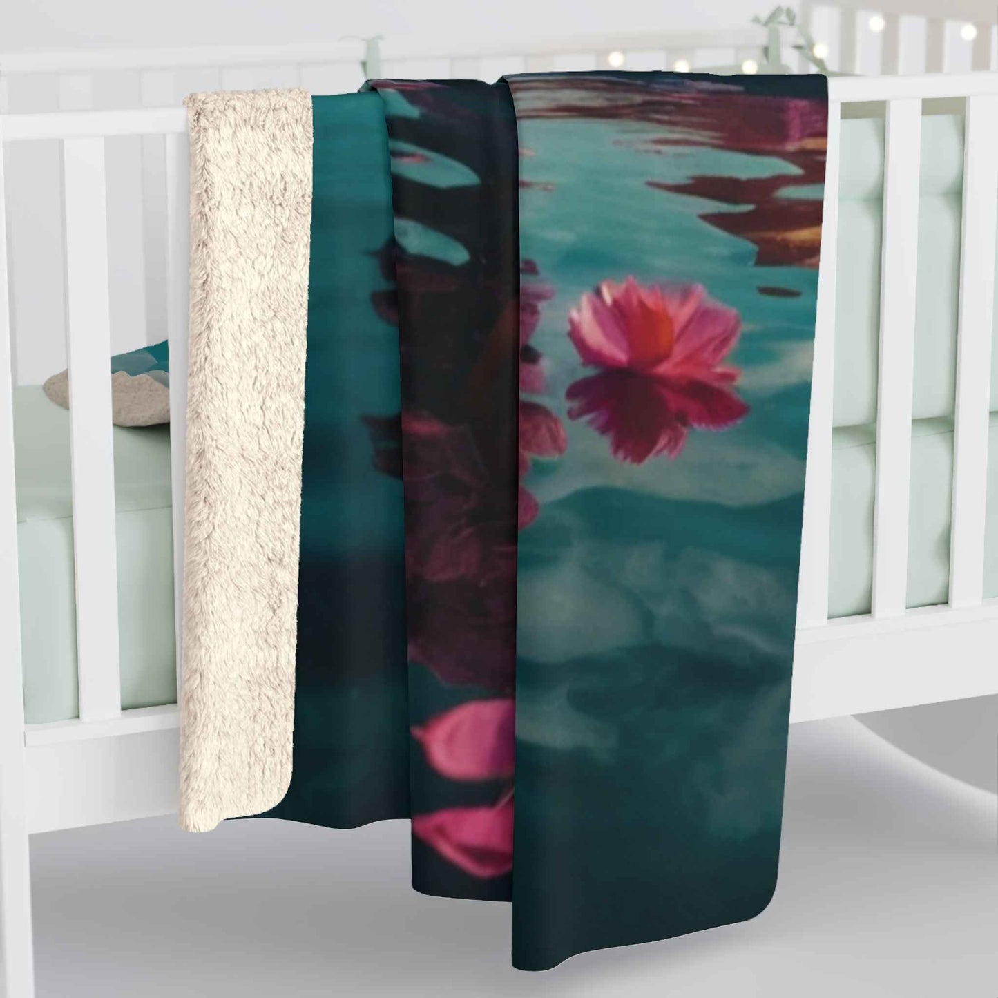Teal fleece throw with close-up pink flower and leaf print, draped over edge