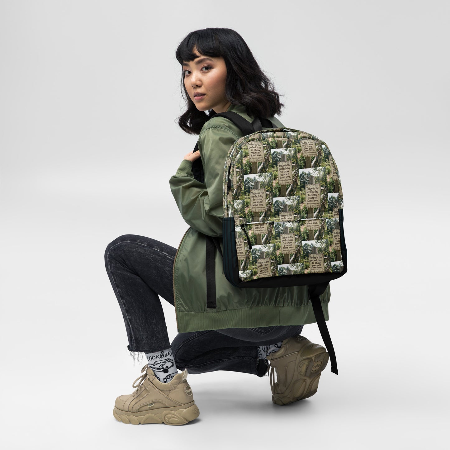 Printed canvas backpack with black straps and front panel pocket, worn while sitting