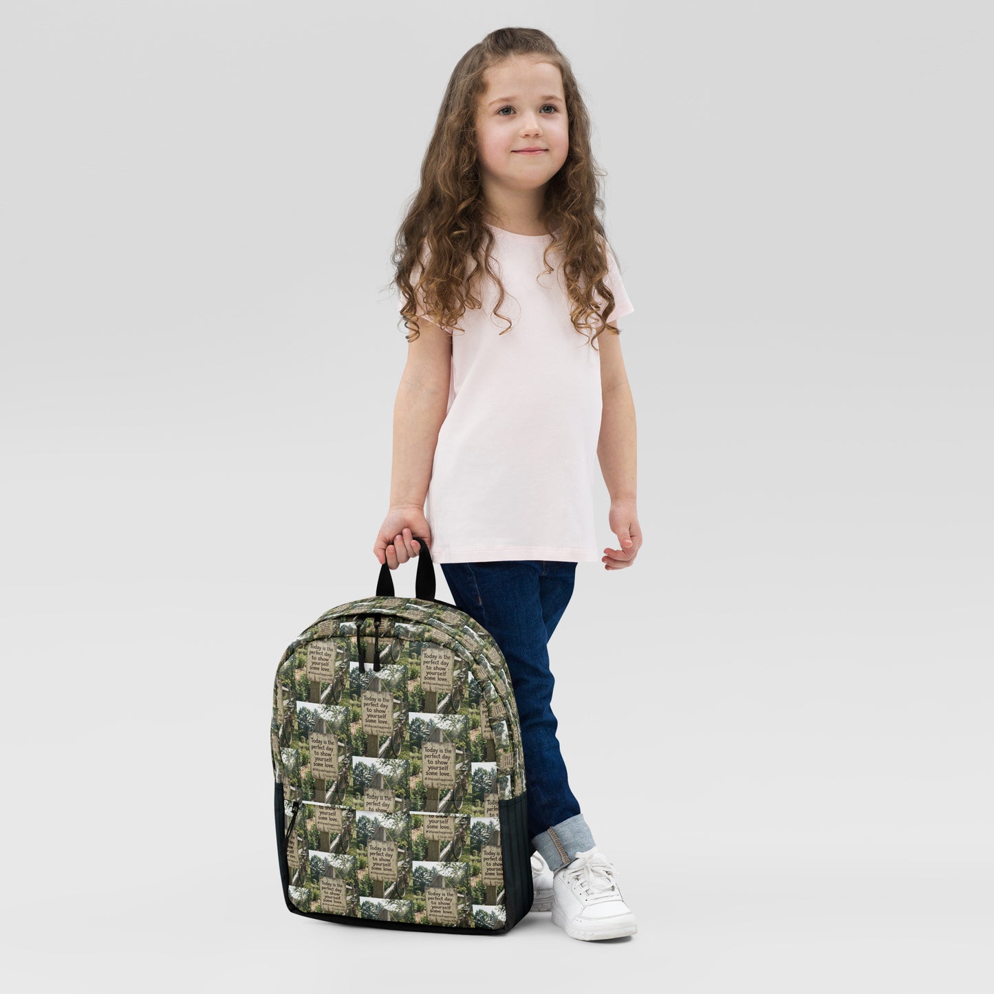 Printed canvas backpack with black straps, worn by a child with white shirt