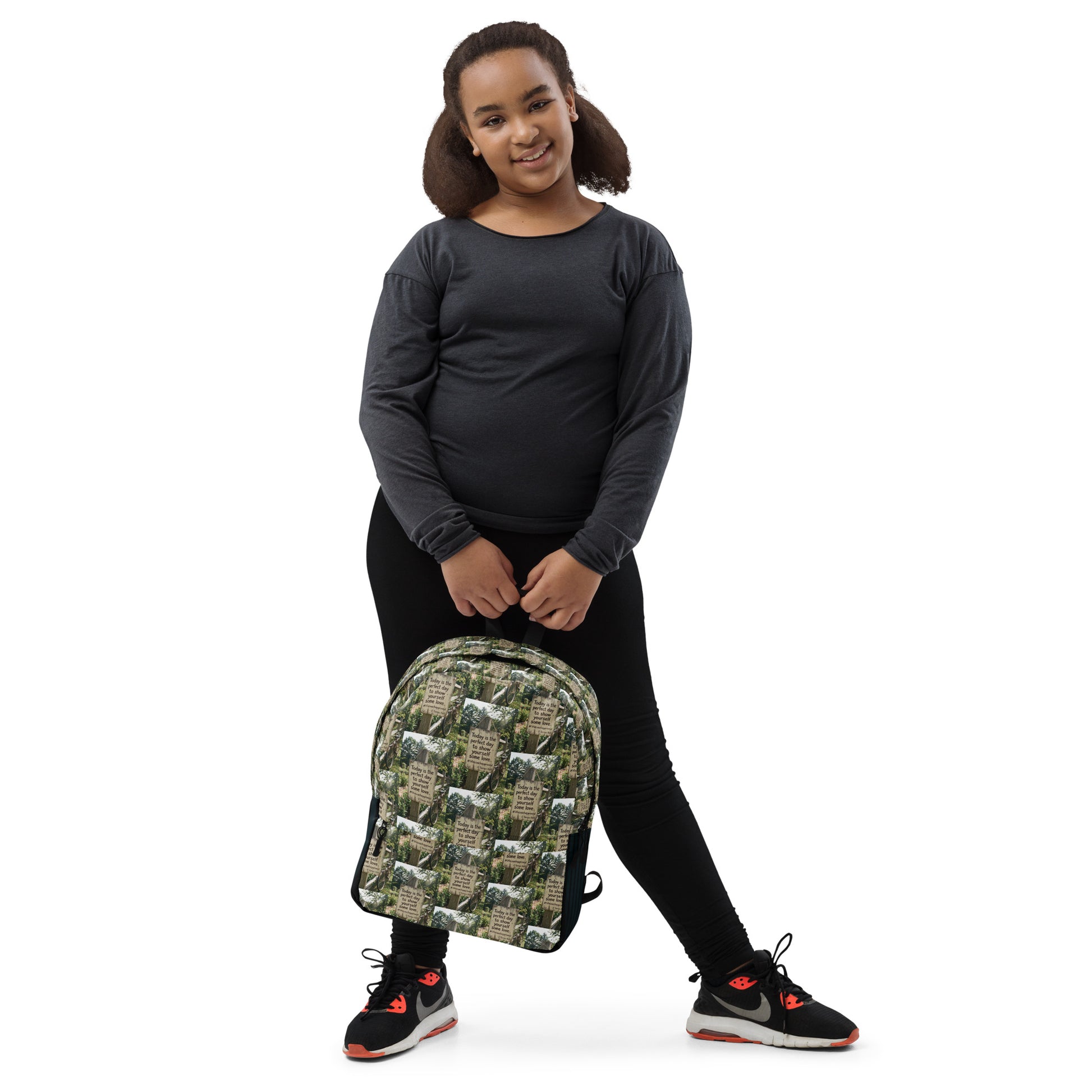 Green leaf-print self-love backpack with quote collage, black straps and top handle.