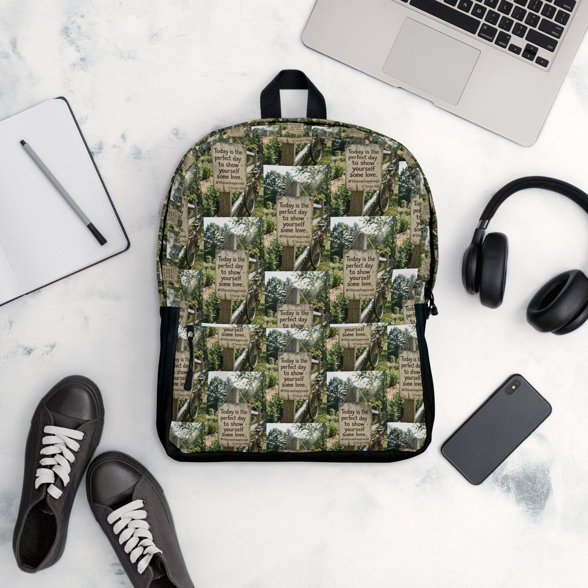 Green quote collage backpack with black bottom, front pocket, and zip-top opening.