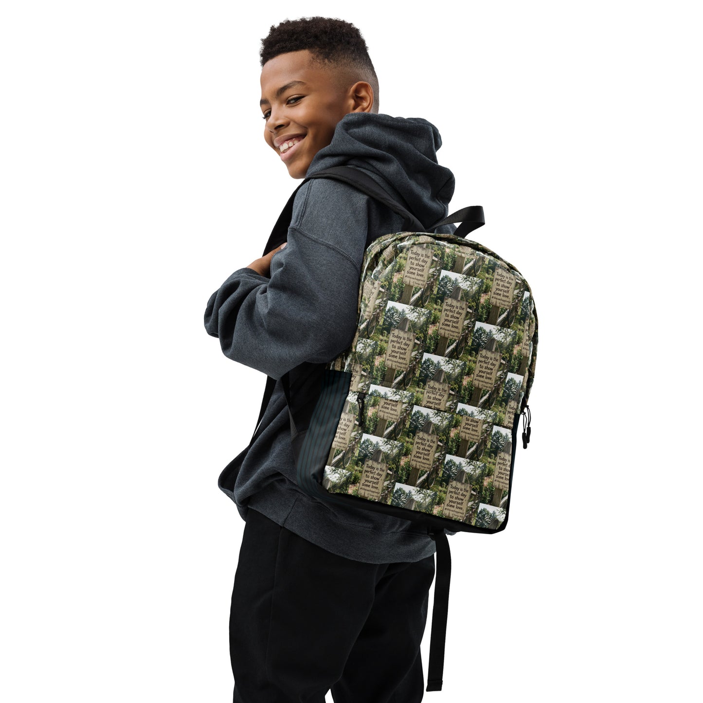 Self love backpack on person, green-and-beige collage print with black top handle