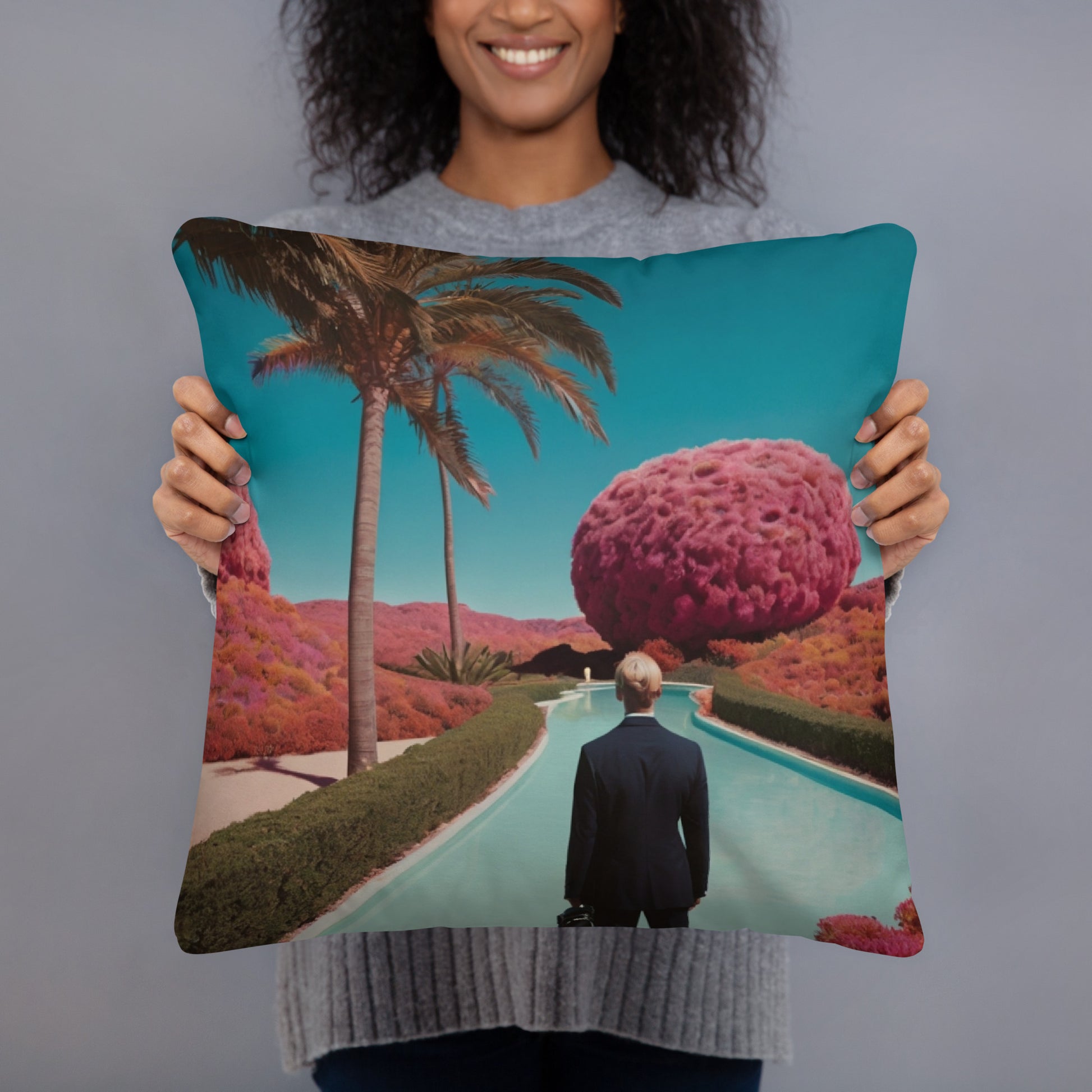 Square teal accent pillow held up, showing a palm path with purple tree and lake