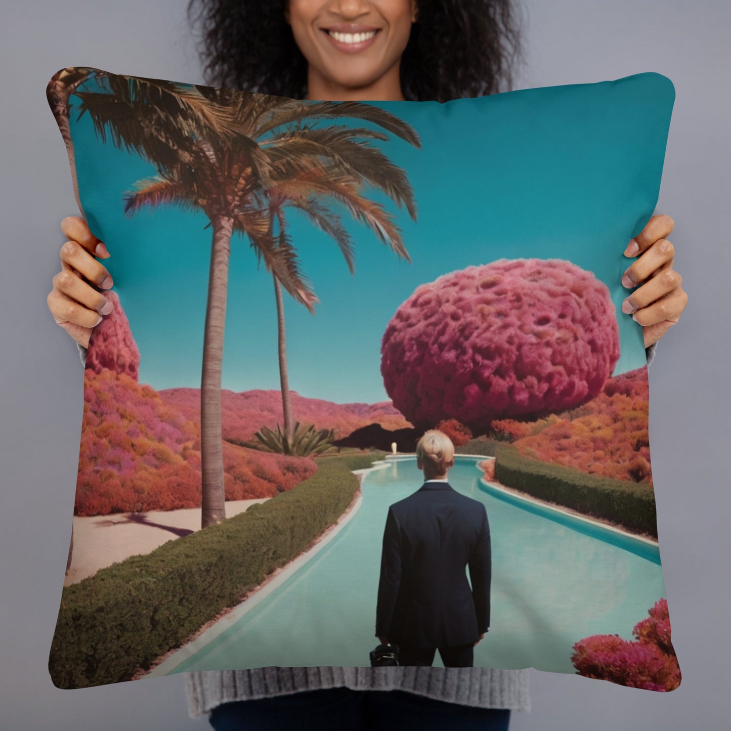 Square teal accent pillow held up, showing a palm-lined road with a purple tree