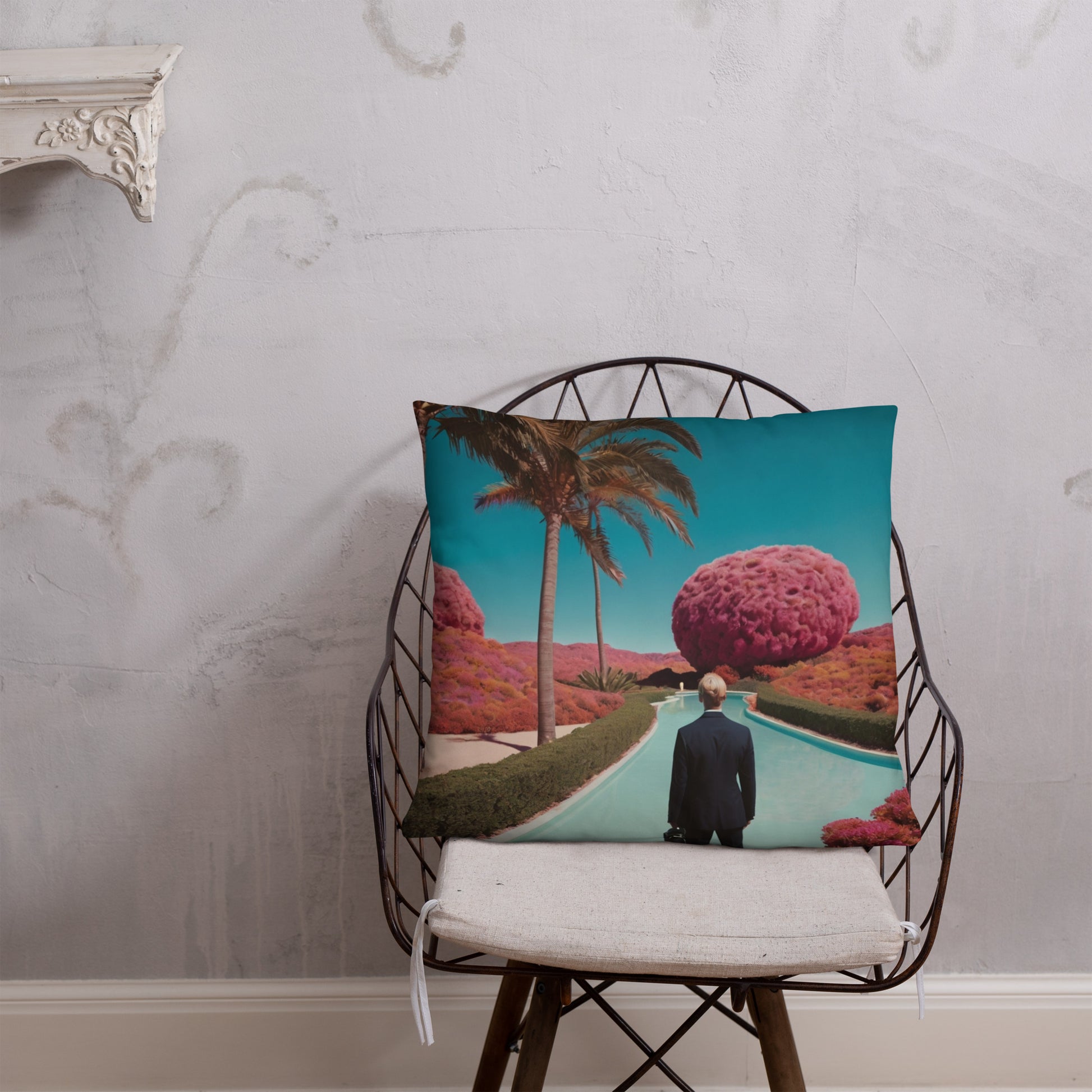 Teal accent pillow featuring a man by a pool, palm tree, and pink mushroomlike hills