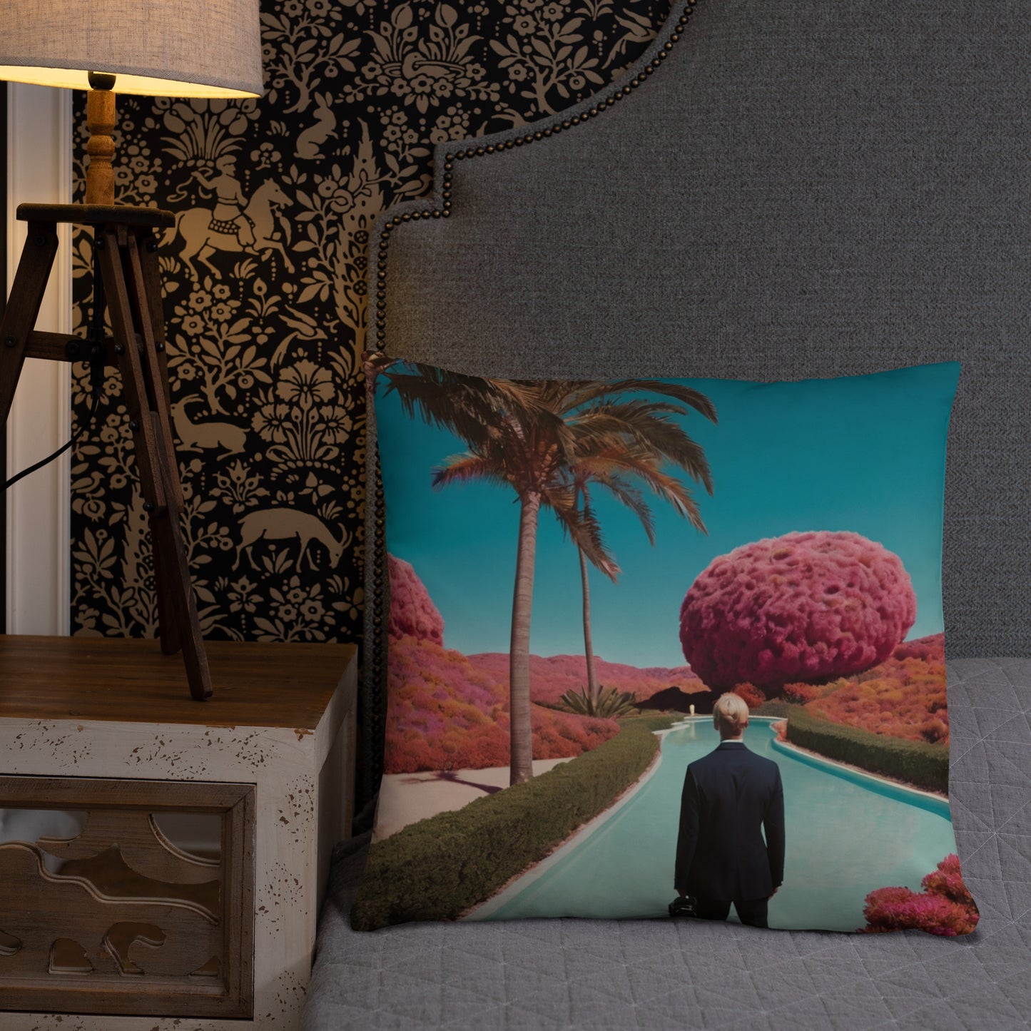Teal accent pillow with a scenic pool, palm trees, and a man facing a large pink sphere