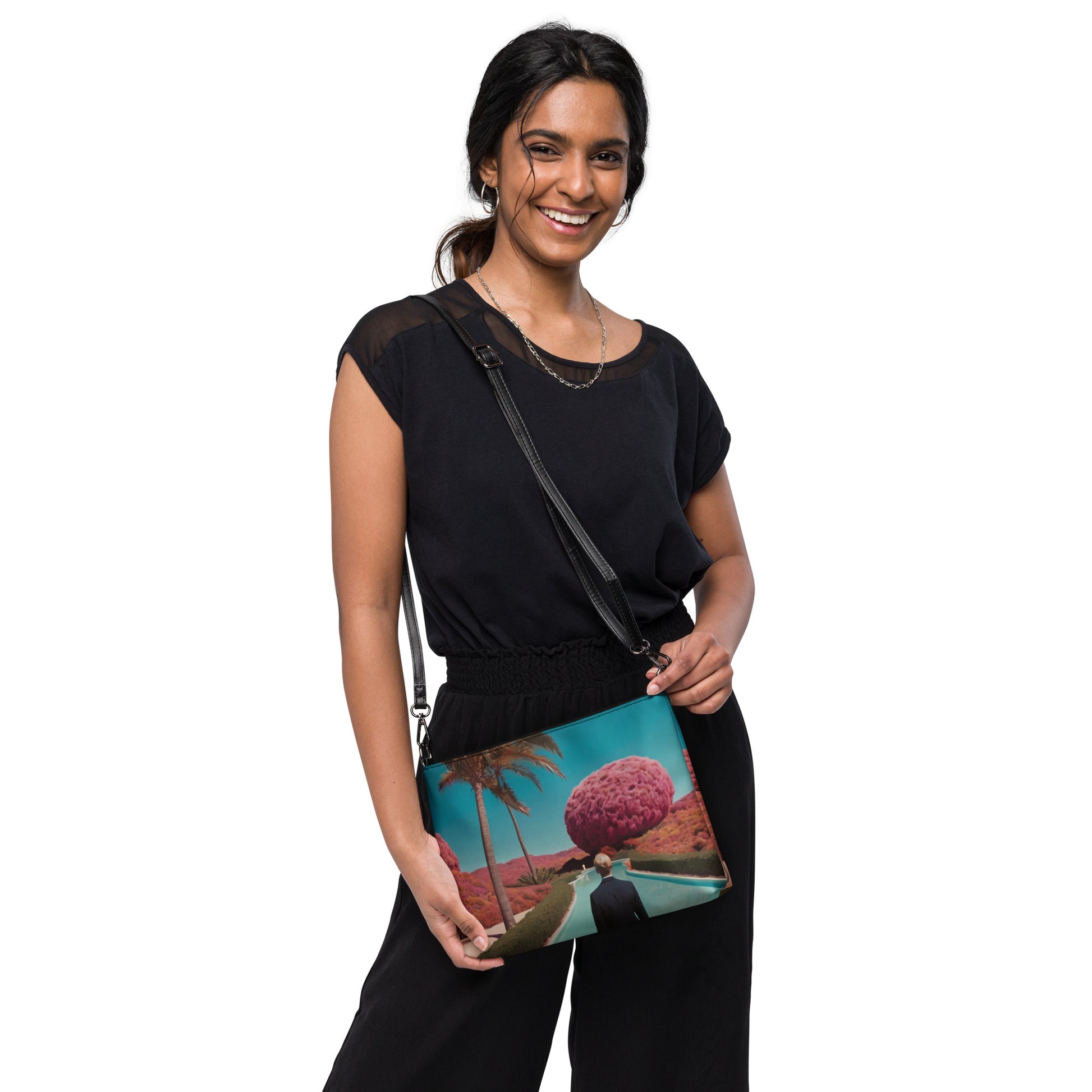 Teal crossbody bag with zipper and scenic print, worn with black outfit