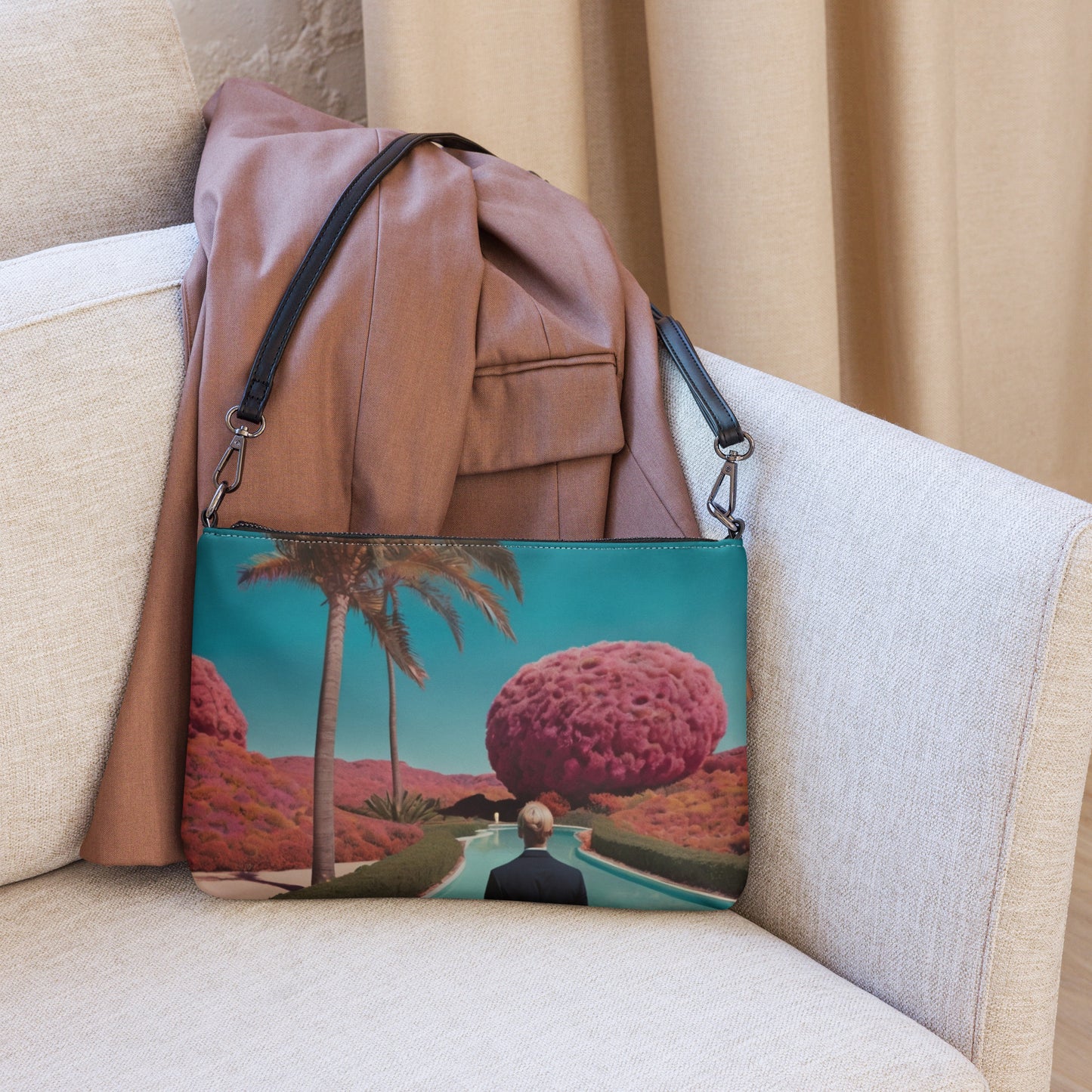 Unisex crossbody bag with teal scenic print, black straps, and top zipper on couch.