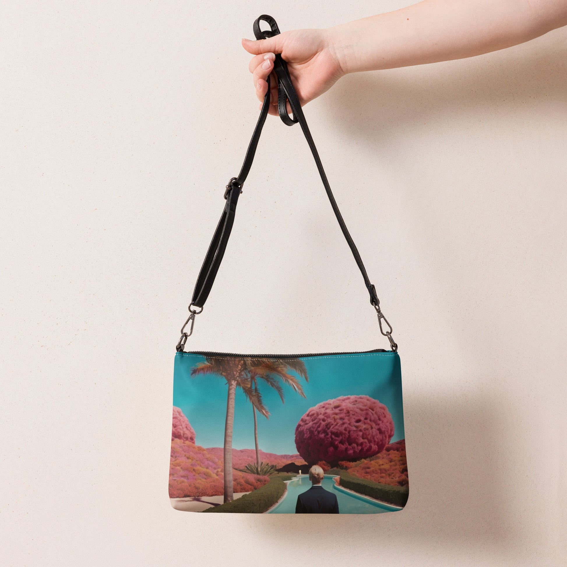 Unisex crossbody bag held by a black strap, teal scenic print front pouch.
