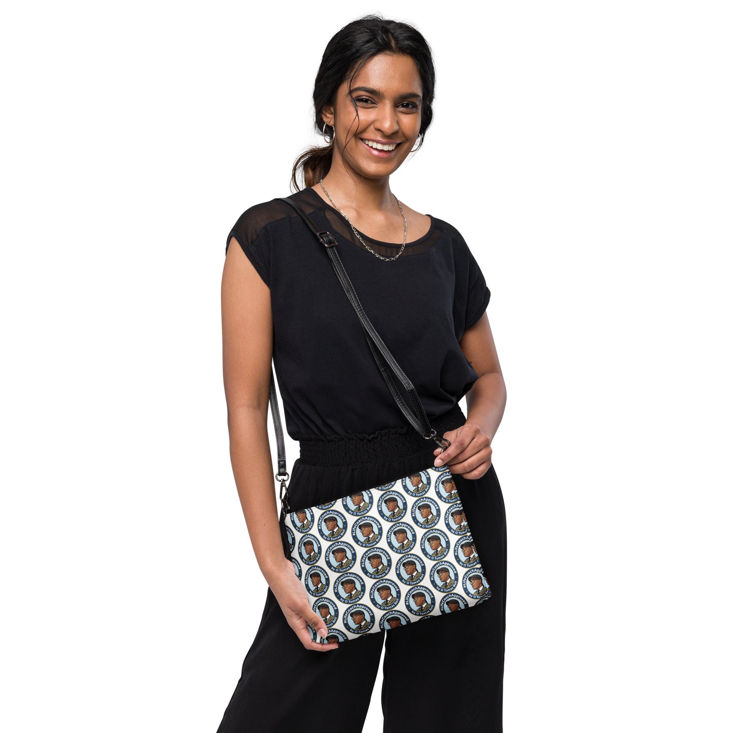 Printed crossbody bag worn by model, black strap and zipper top with blue circular pattern