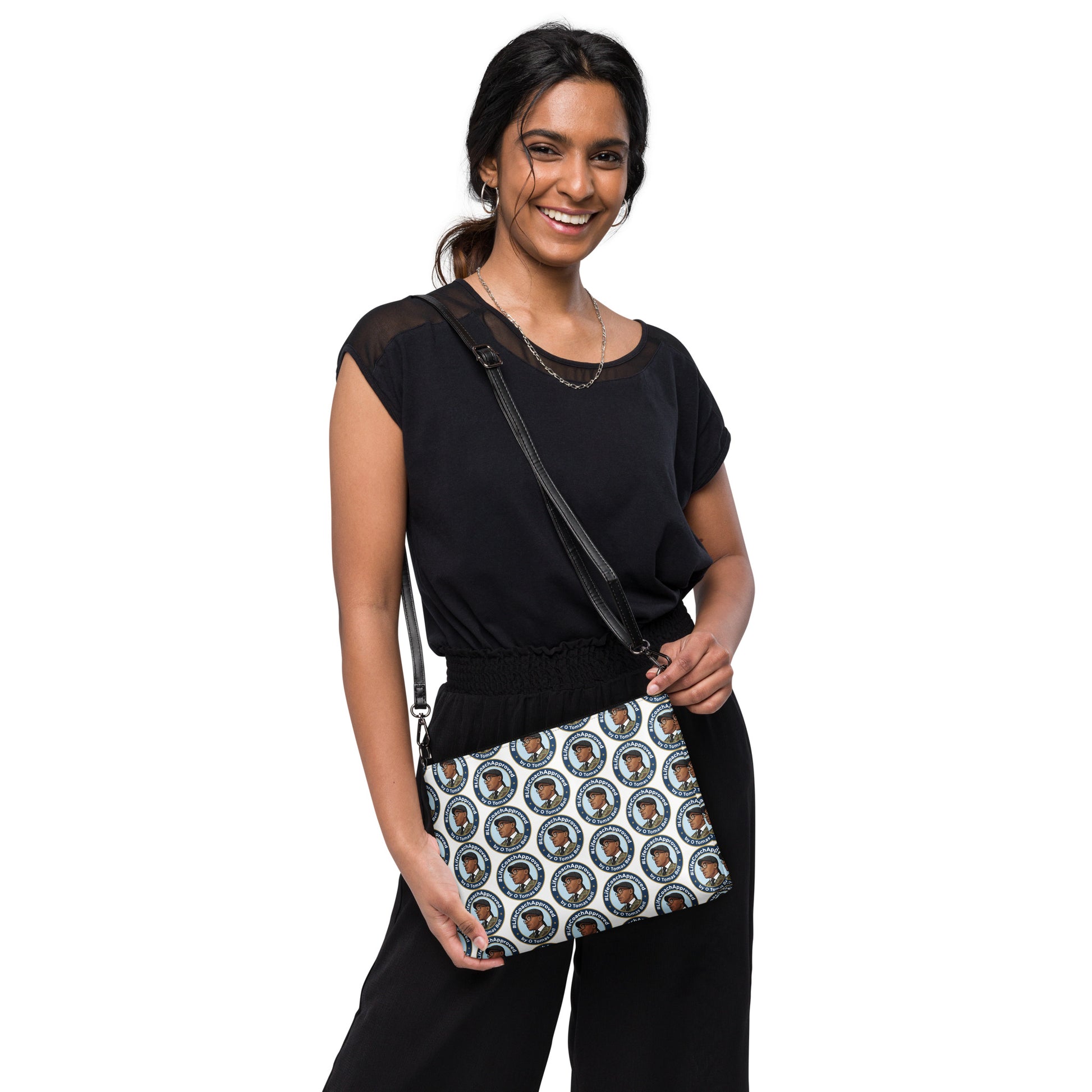 Printed crossbody bag worn by model, black strap and zipper top with blue circular pattern