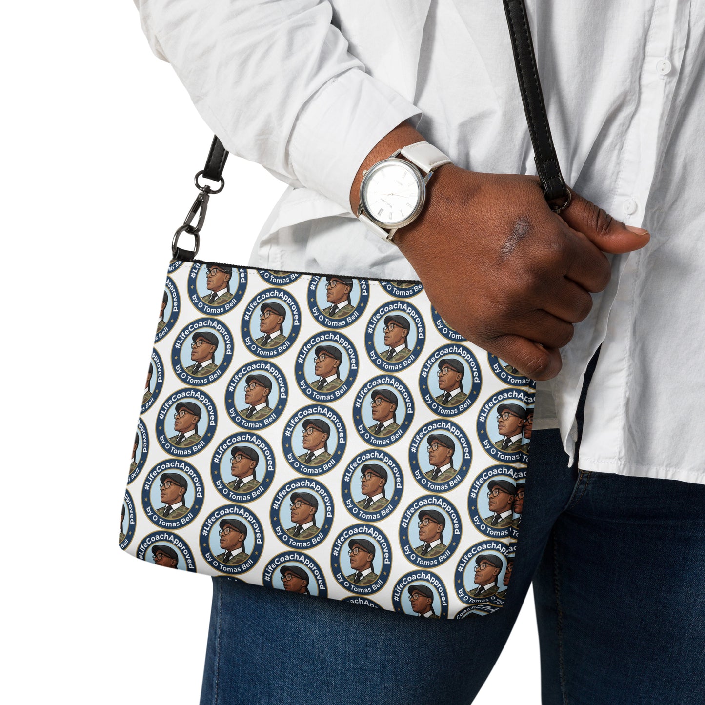 Printed crossbody bag on shoulder with black strap and zipper top, blue circular pattern close-up