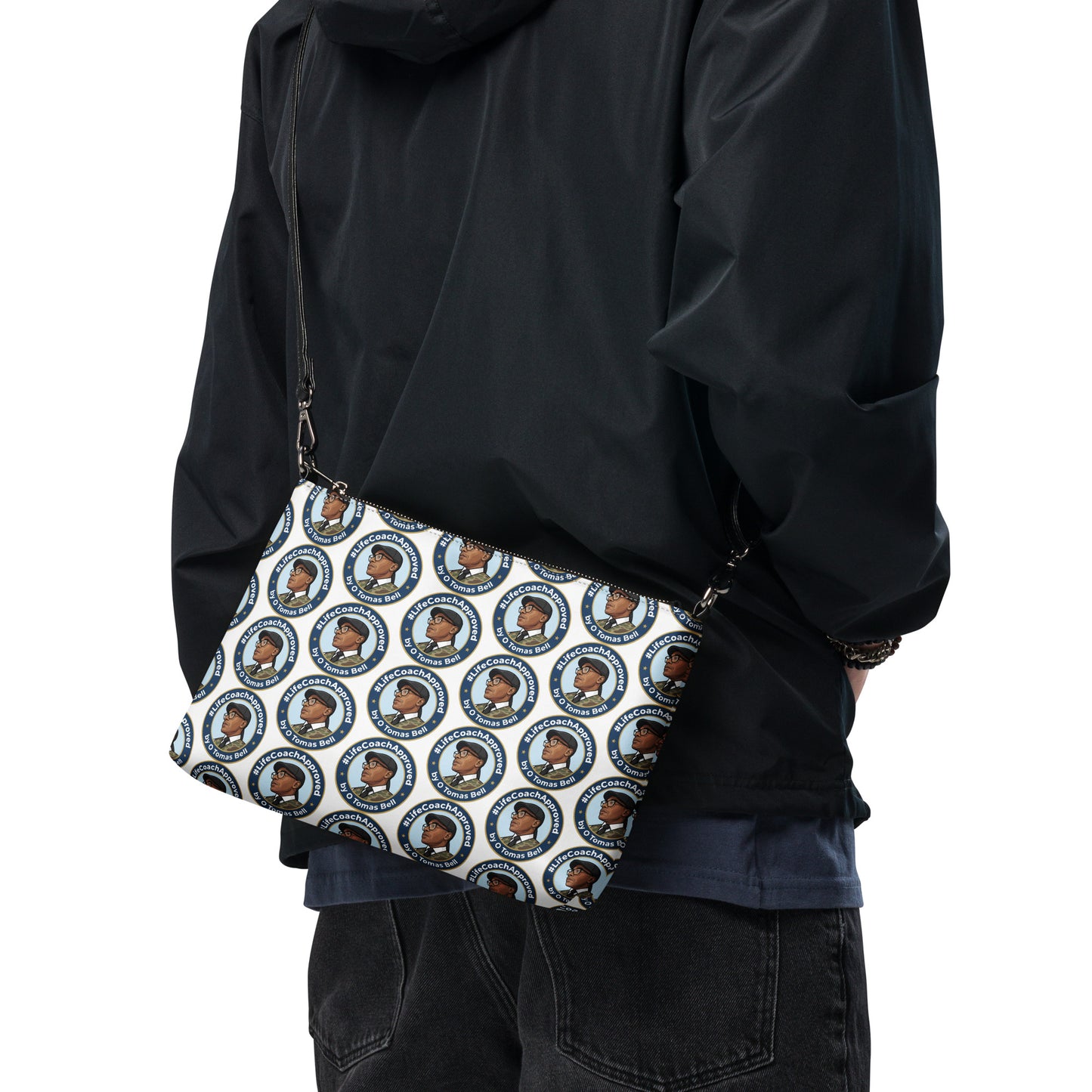 Printed crossbody bag worn across body with black strap and zipper top, blue circular pattern