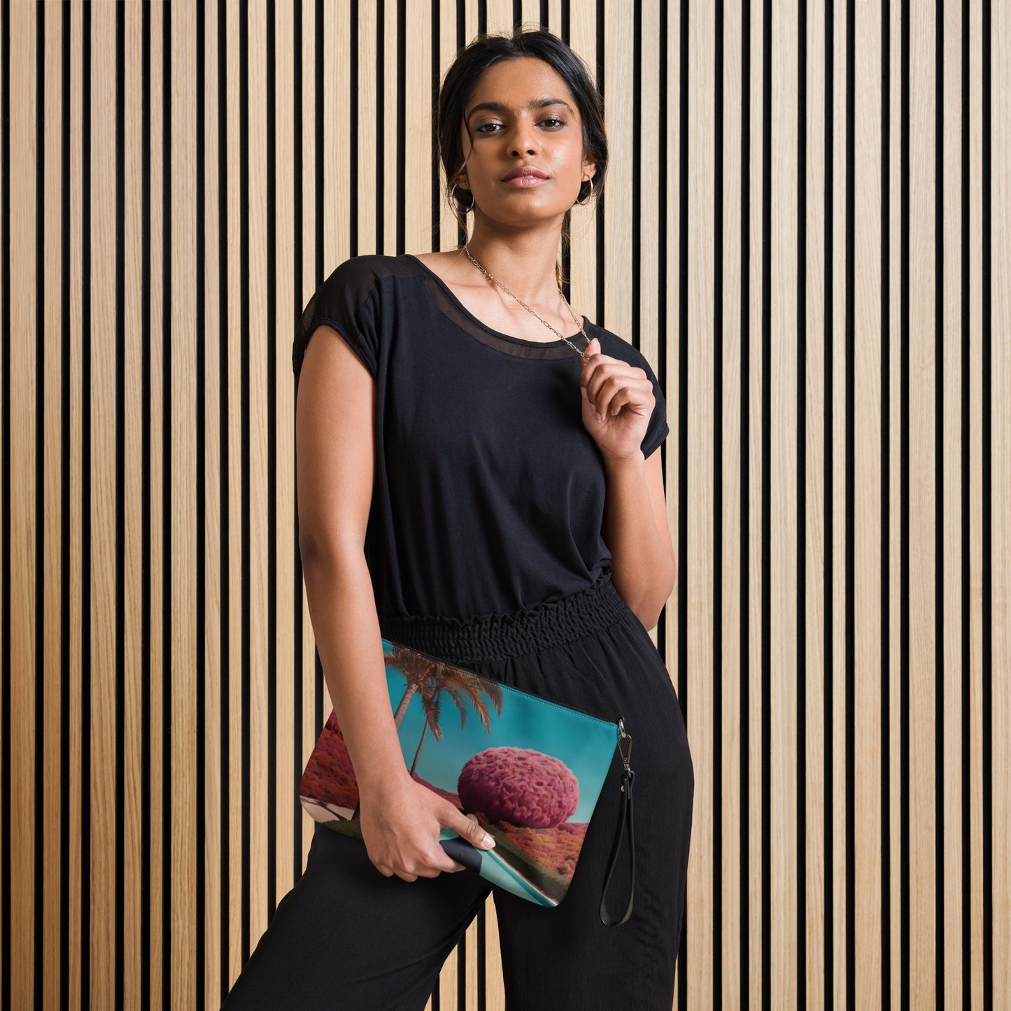 Teal crossbody bag with zipper and scenic print, worn with black dress