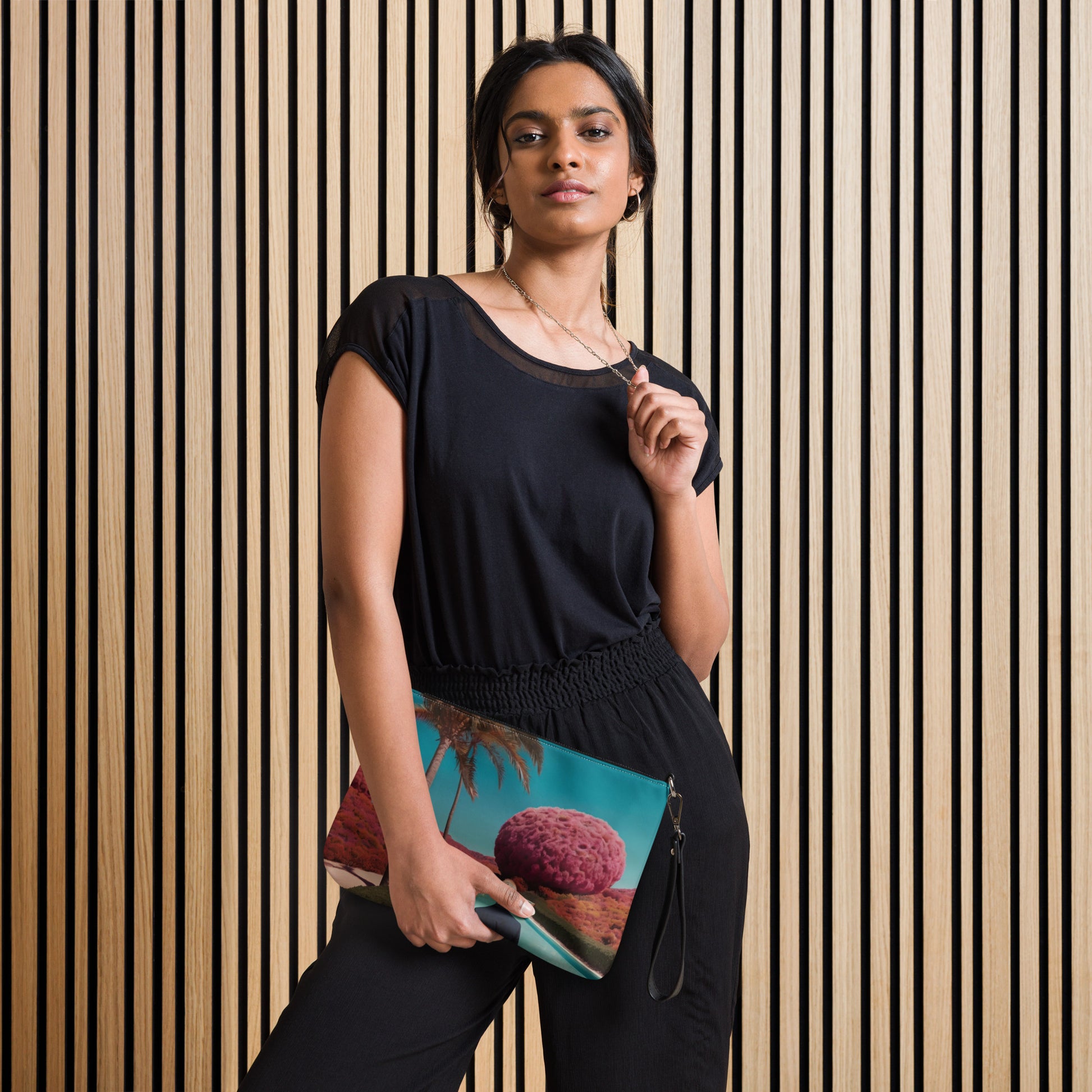 Teal crossbody bag with zipper and scenic print, worn with black dress