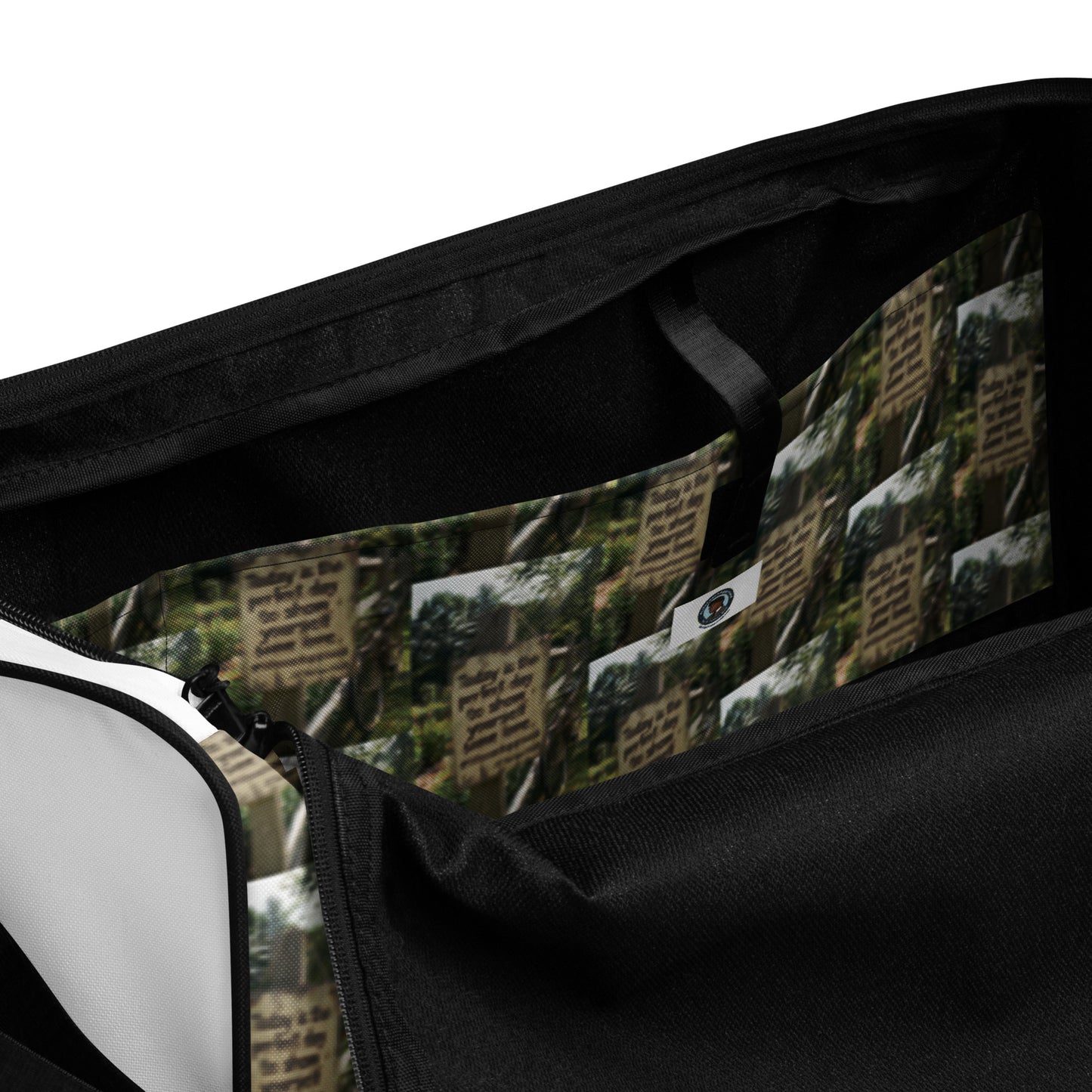 Duffle bag interior close-up with black lining and green tree-text patterned fabric; zipper detail.