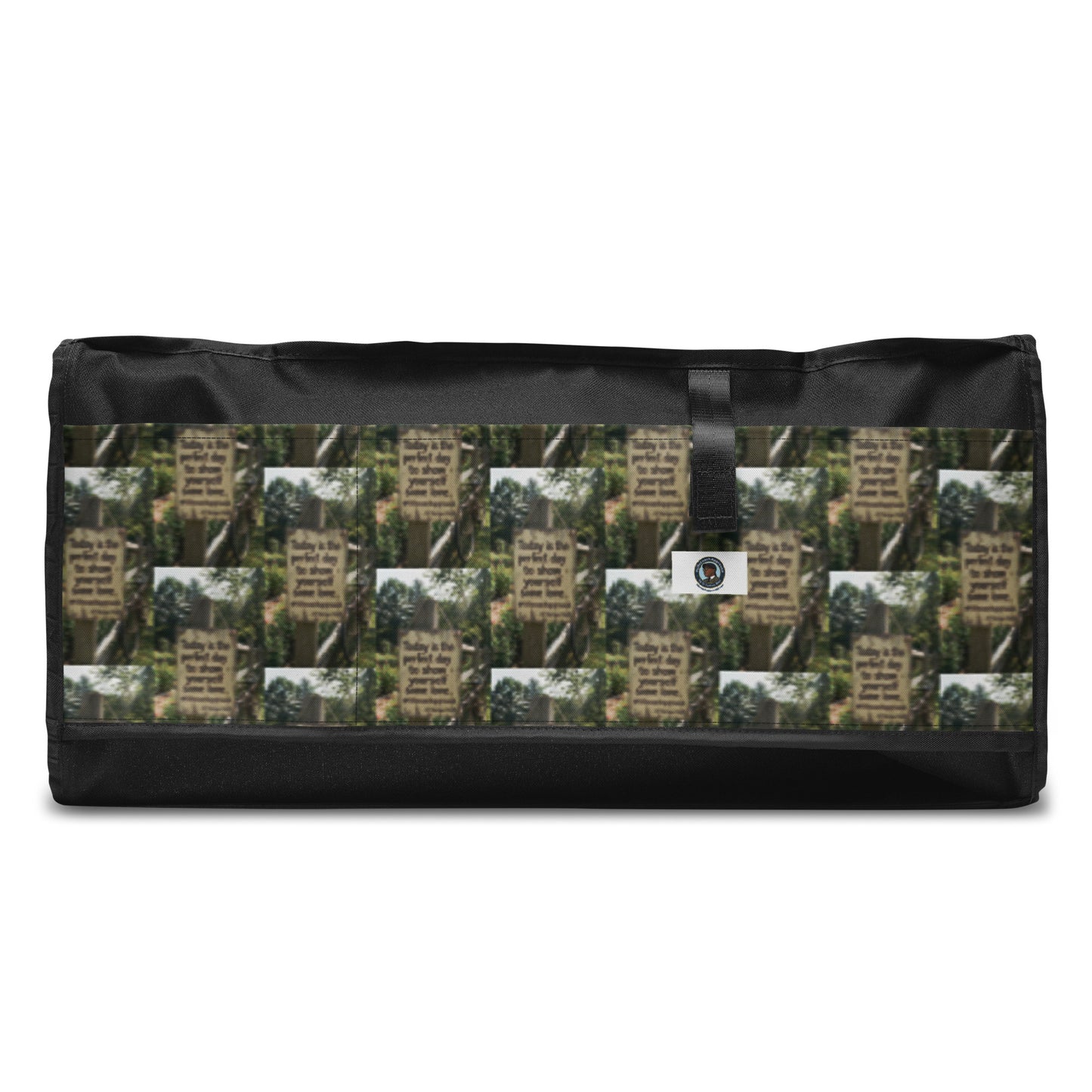Black rectangular duffle bag with forest-and-quote graphic panel and small logo patch.