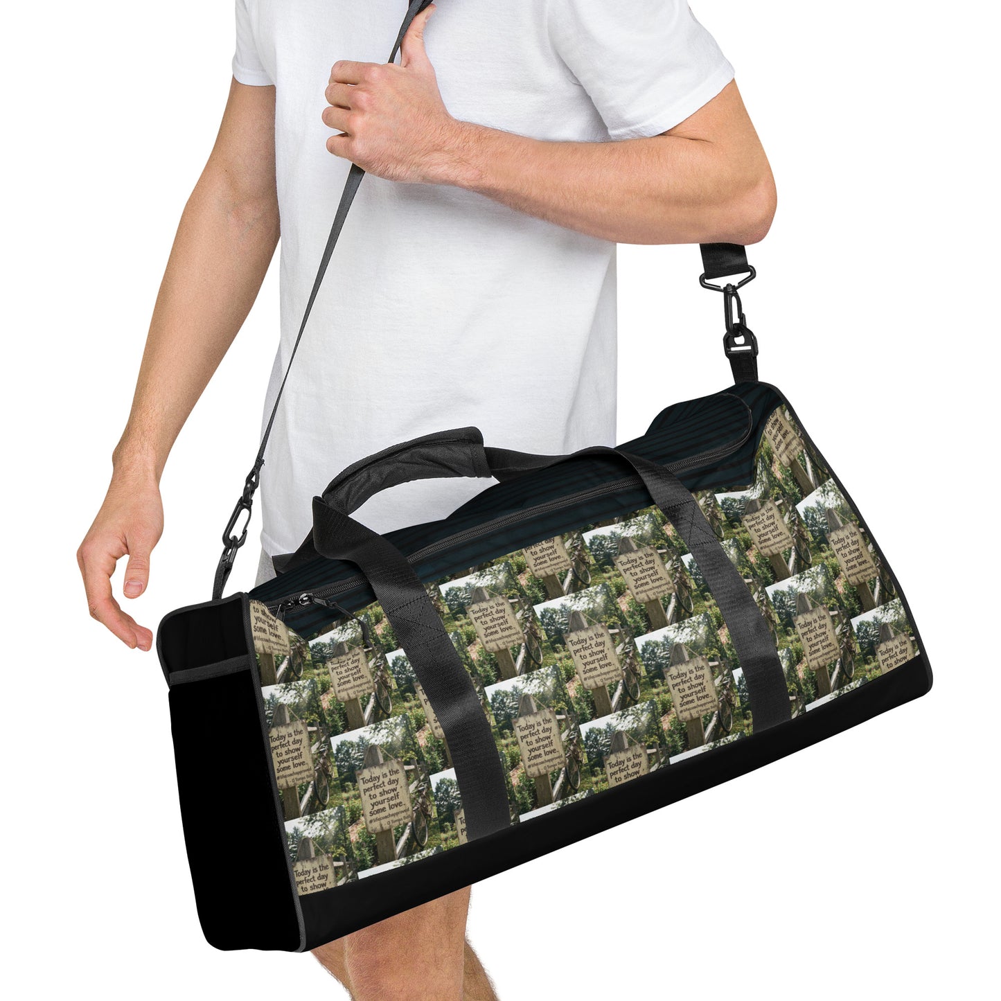 Black duffle bag with adjustable shoulder strap and forest-and-quote graphic front panel.