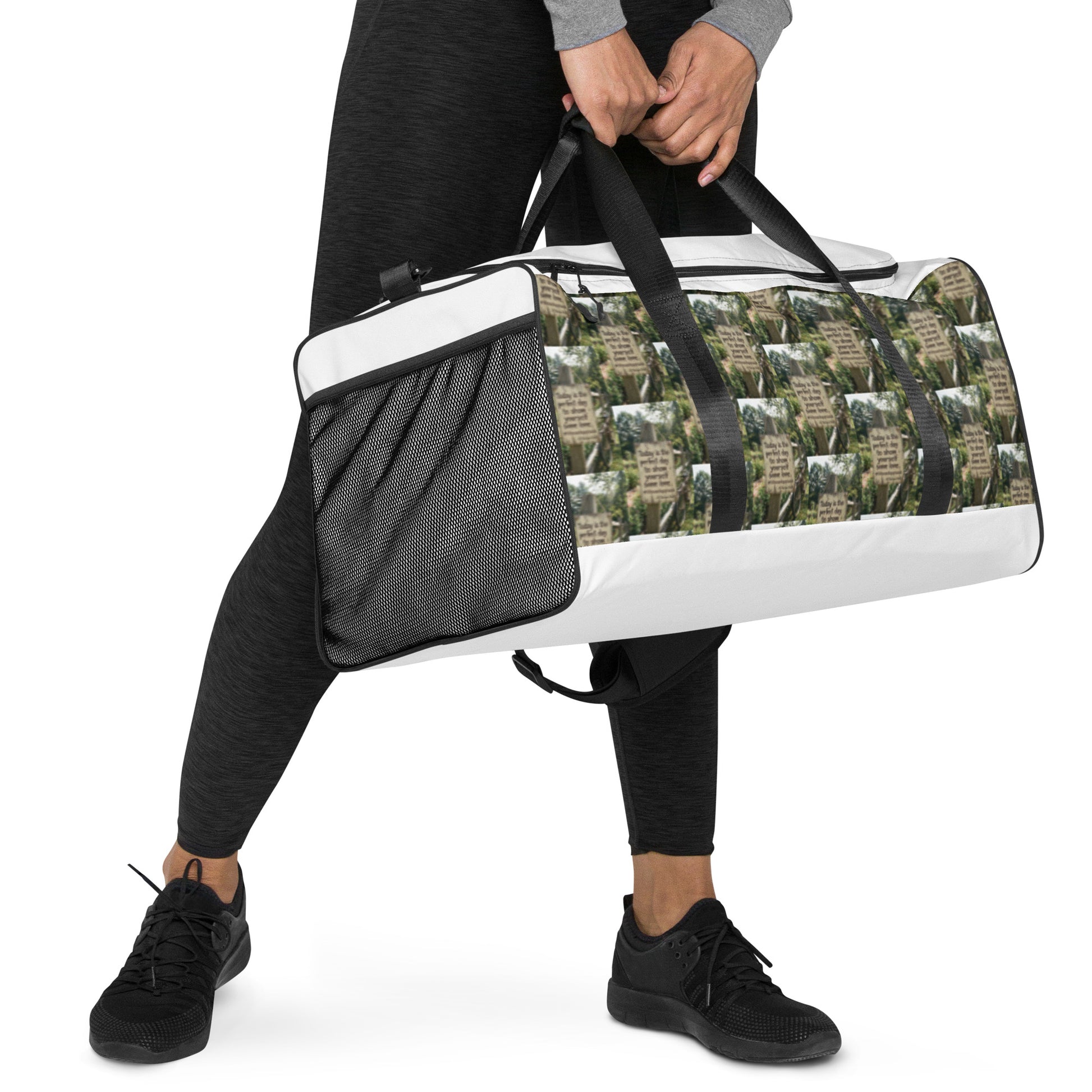 White duffle bag with black mesh side pocket panel and green-brown graphic print