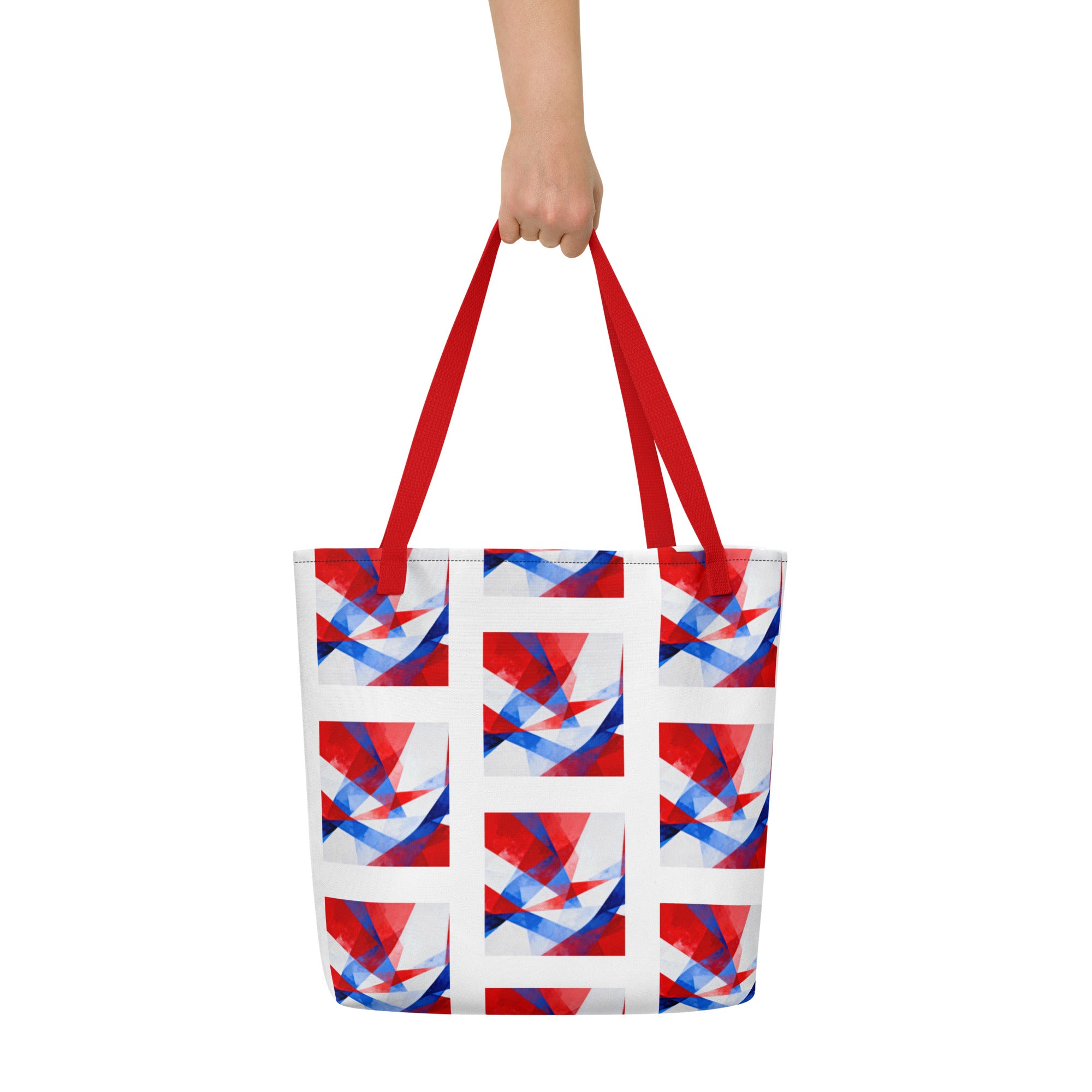 Beach tote bag held by red handles, featuring white, red, and blue geometric pattern