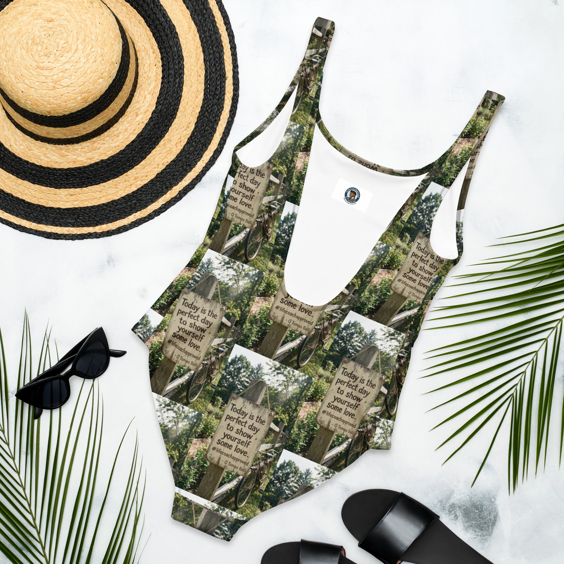 Self love one-piece swimsuit with green-and-white woodland sign graphic and thin straps.