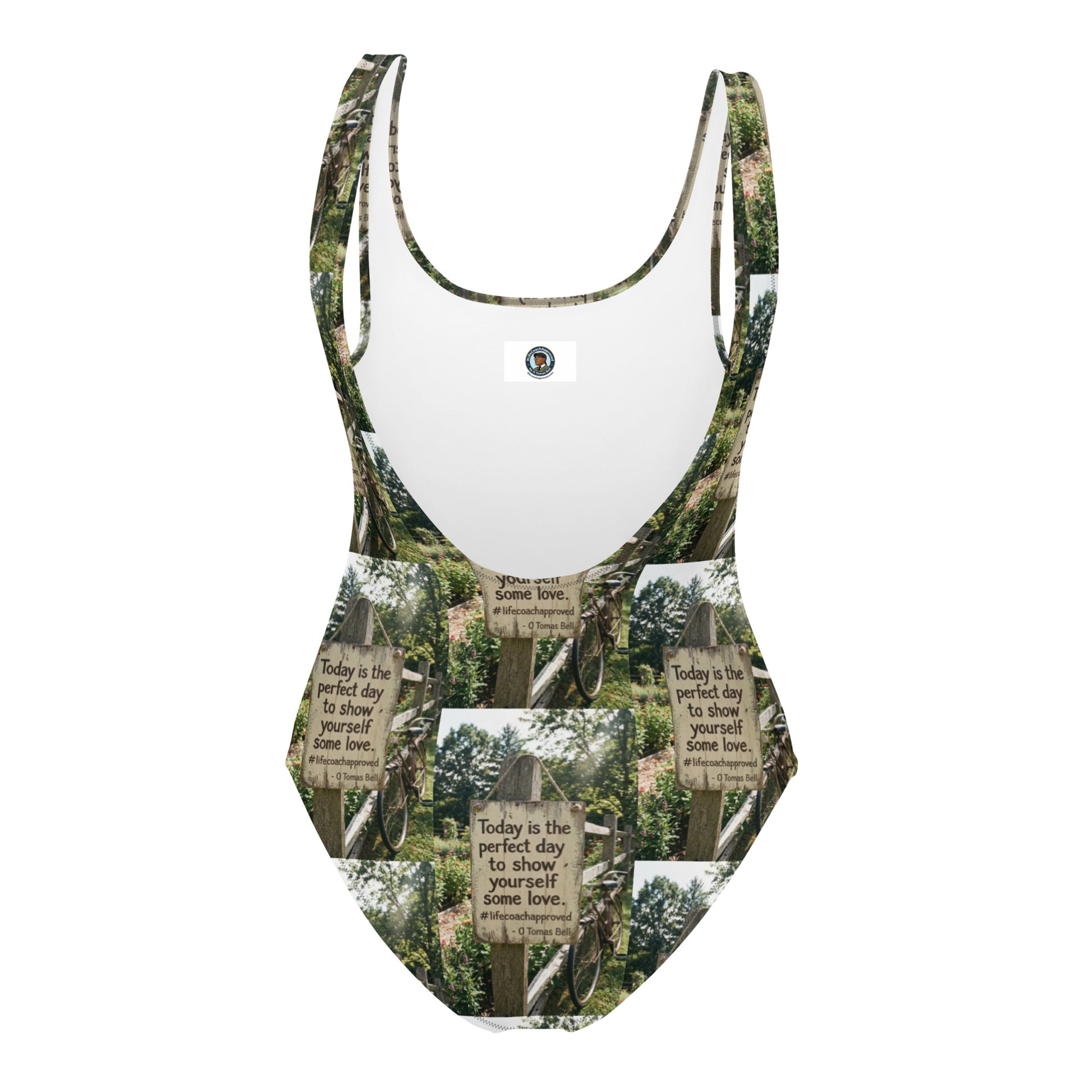 Self love one-piece swimsuit with green-and-white sign print and small logo patch at chest.