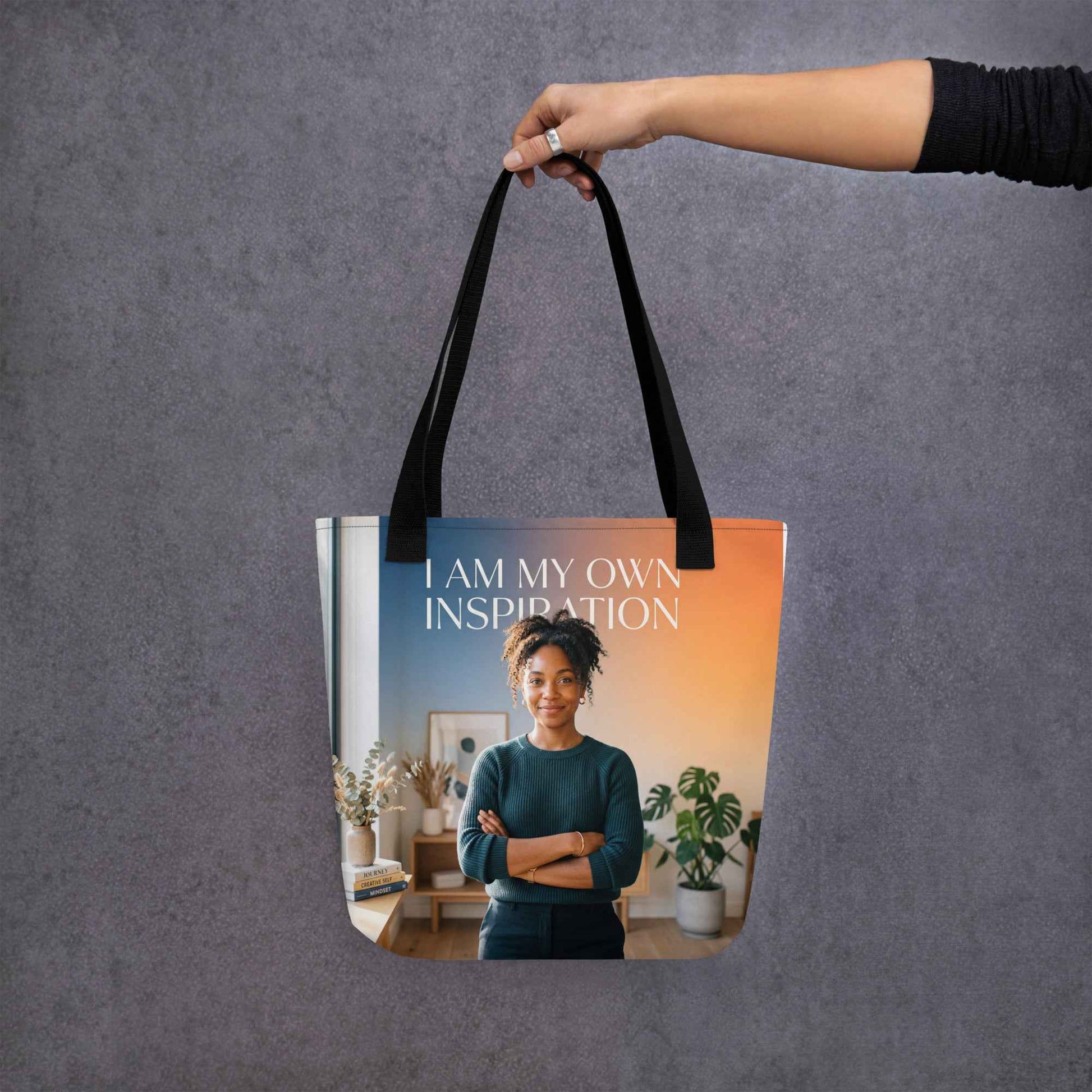 Black tote bag with handles and front panel text 'I AM MY OWN INSPIRATION'