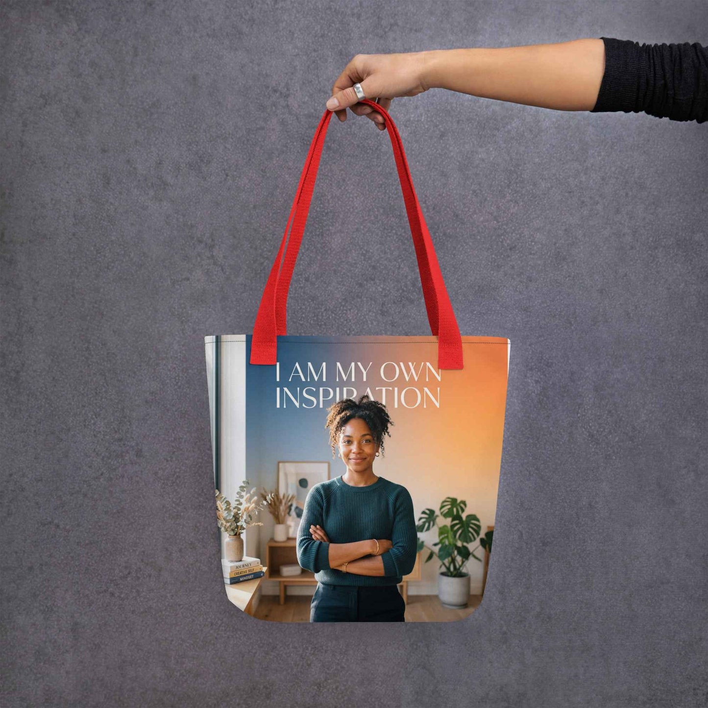 Red tote bag with handles and front panel text 'I AM MY OWN INSPIRATION'