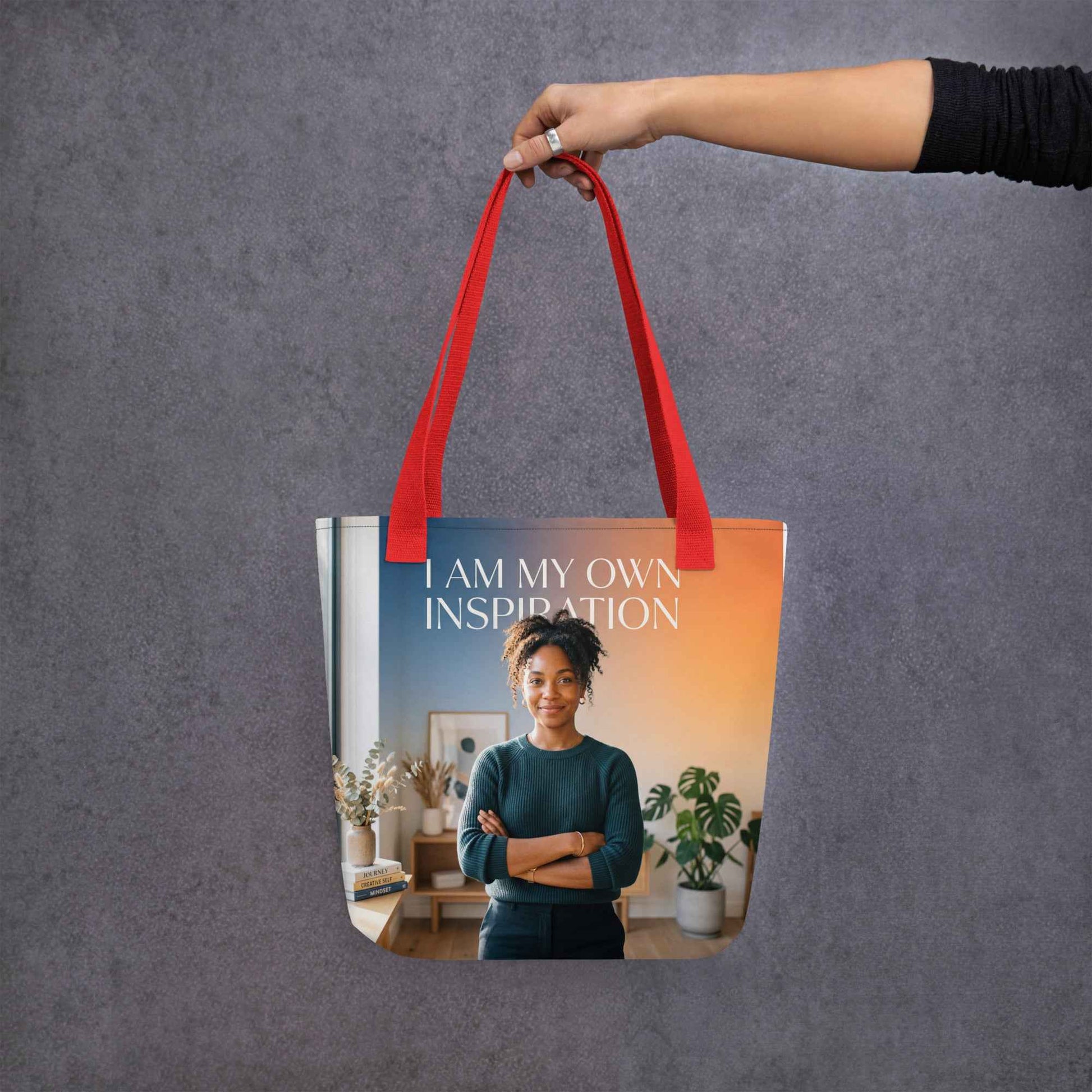 Red tote bag with handles and front panel text 'I AM MY OWN INSPIRATION'