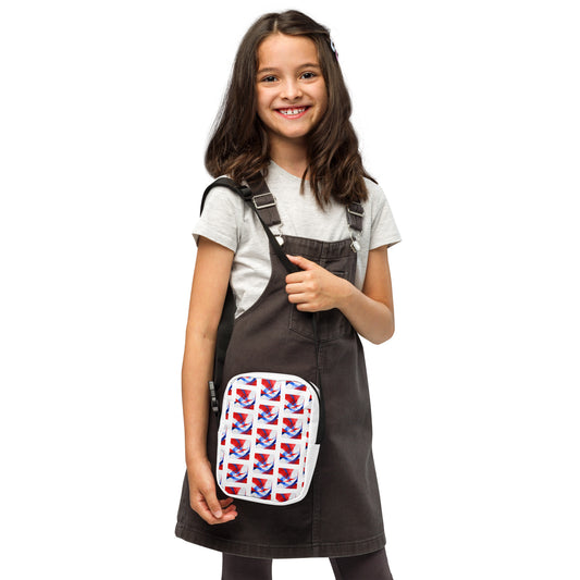 Small white crossbody bag with black straps and red blue flag-style patterned front panel.