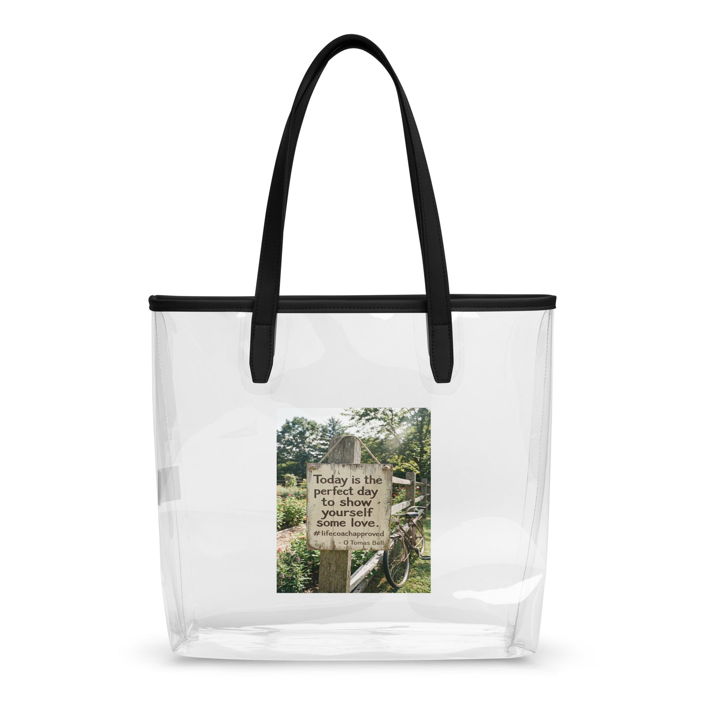 Clear tote bag with black handles and a centered printed inspirational panel