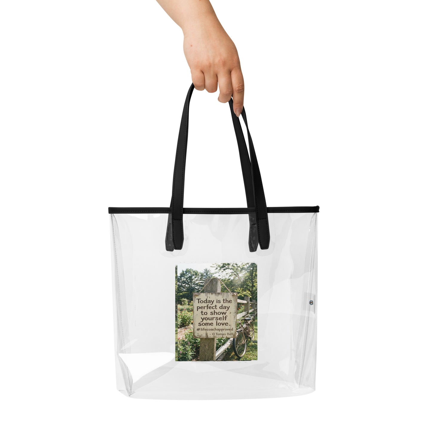 Self Love clear tote bag held by hand with black top handles and front photo graphic
