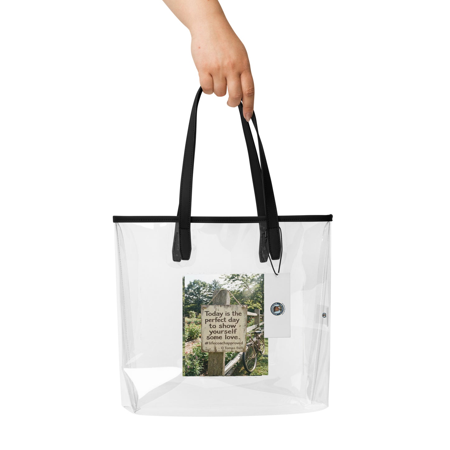 Self Love clear tote bag held by hand, black top handles and front photo graphic