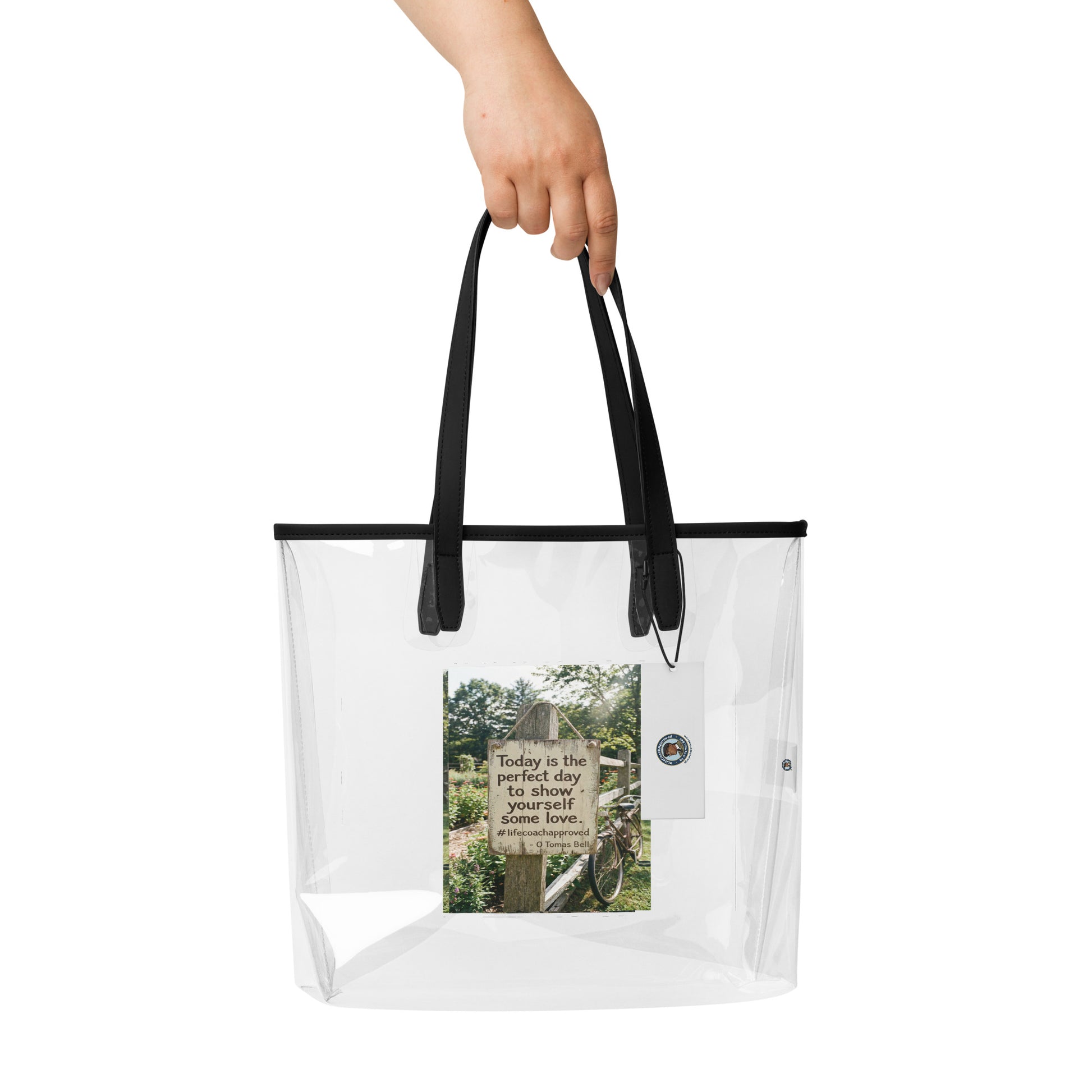 Self Love clear tote bag held by hand, black top handles and front photo graphic