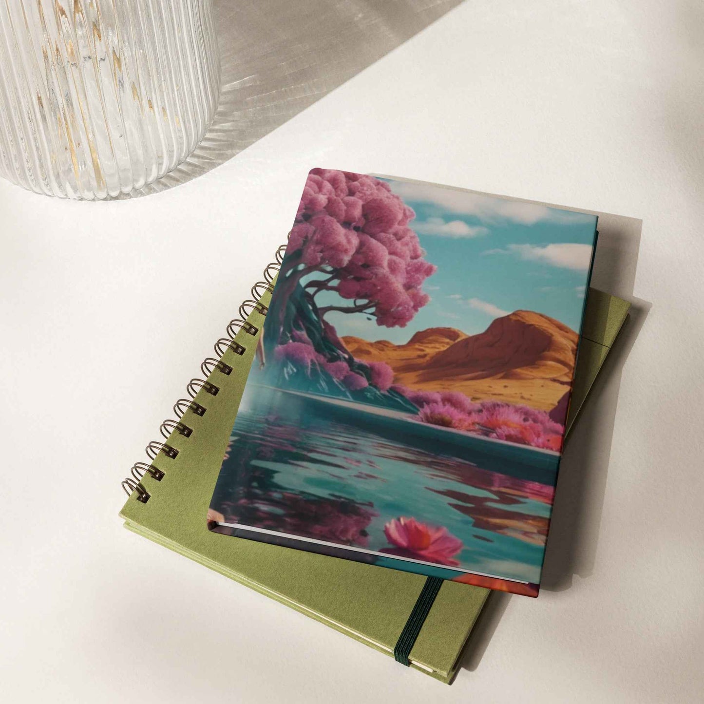 Matte hardcover journal with landscape cover and coil binding; green notebook underneath