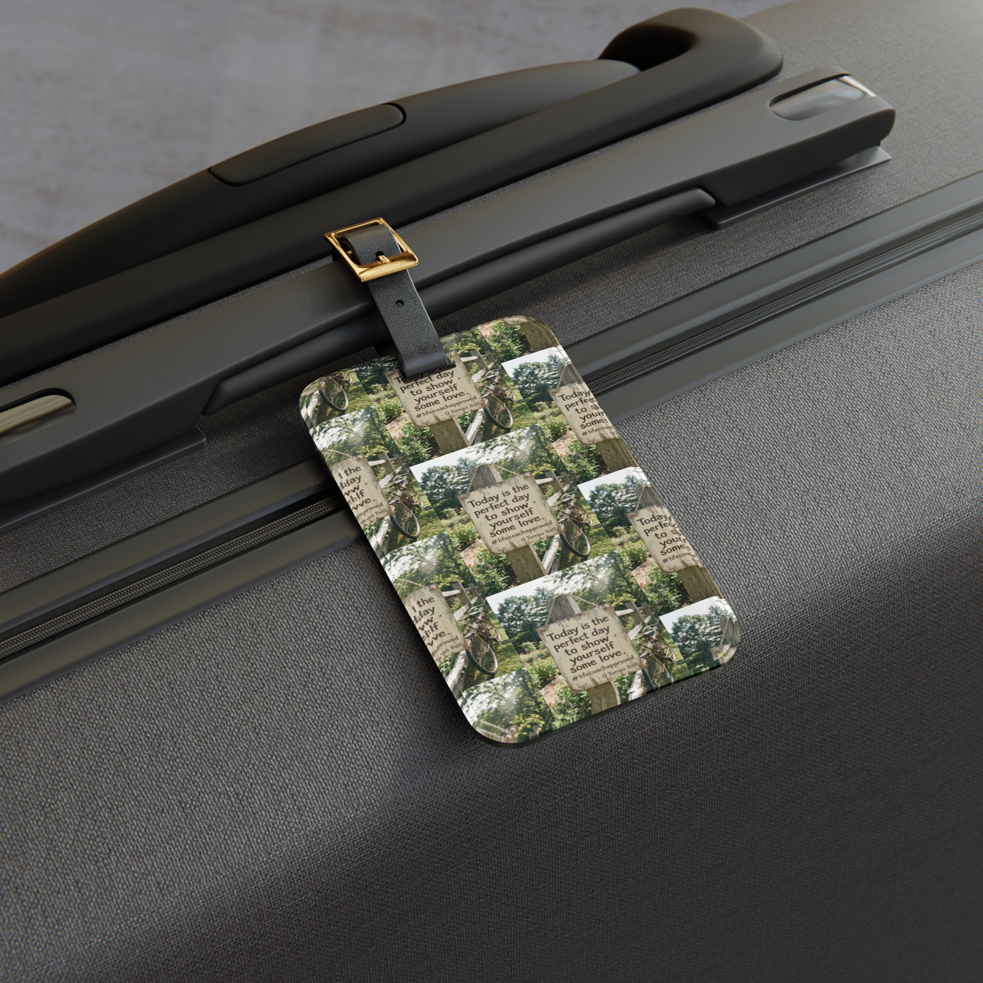 Dark luggage tag with quote-and-nature print, attached with metal clip to suitcase