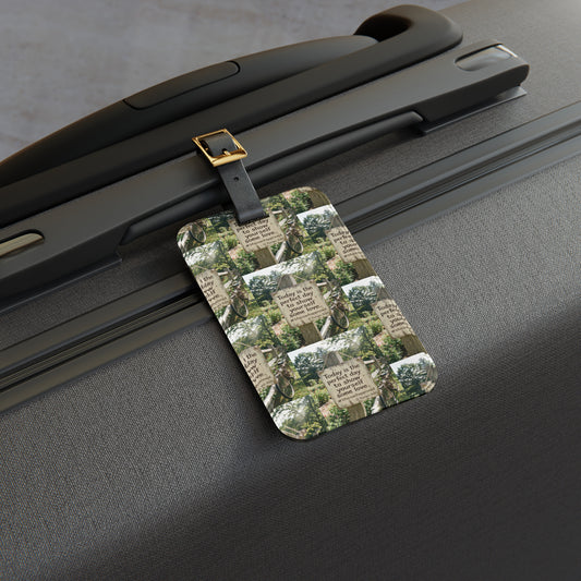 Dark luggage tag with quote-and-nature print, attached with metal clip to suitcase