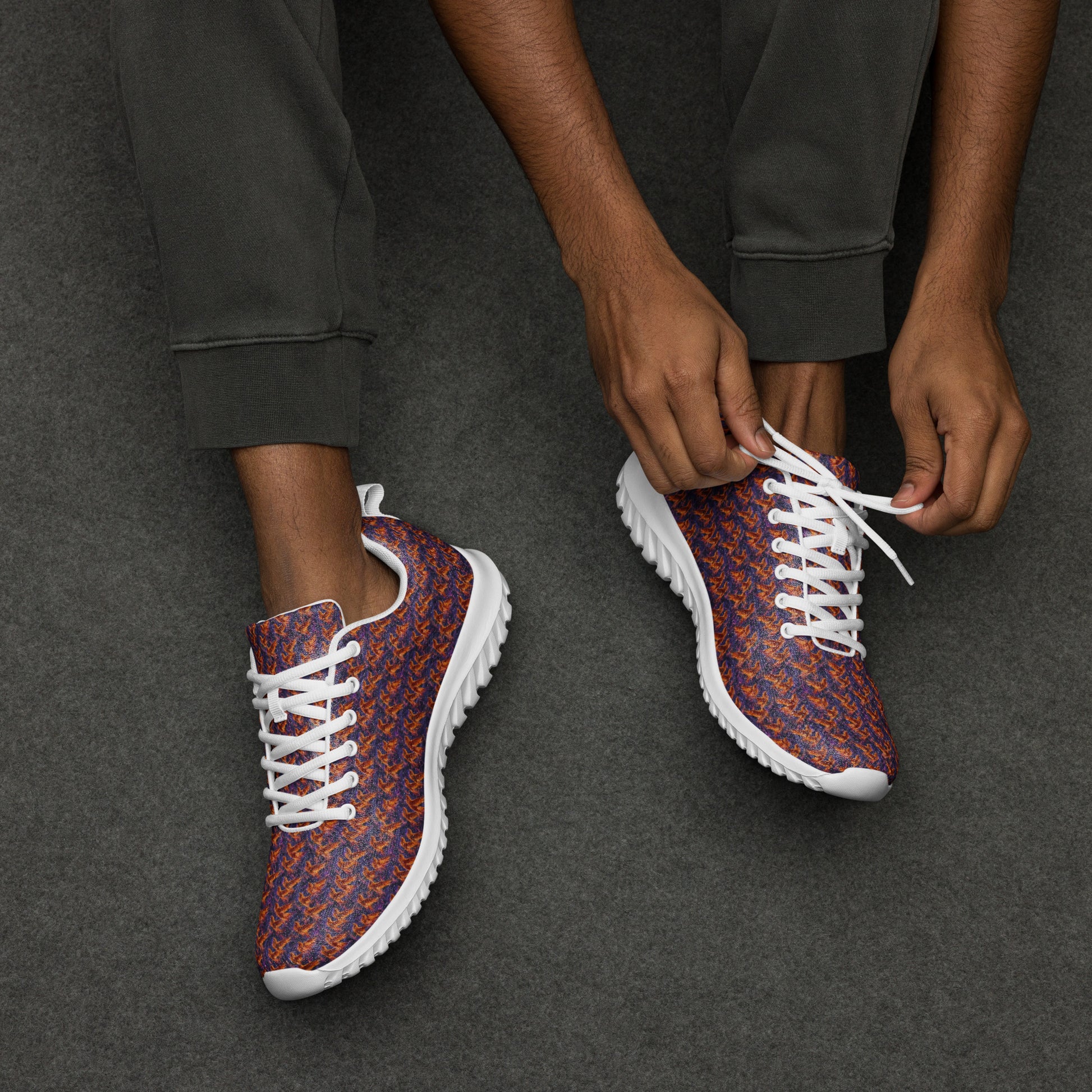 Pair of athletic shoes with orange-and-blue knit upper and white laces on dark pants