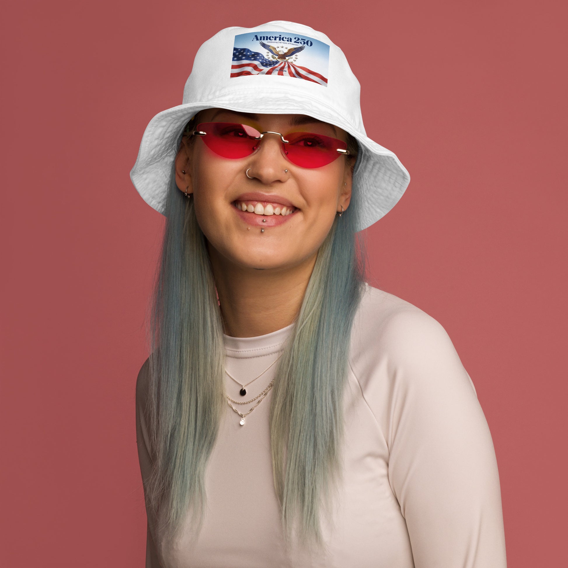 White bucket hat with America-themed patch, worn over straight blue hair.
