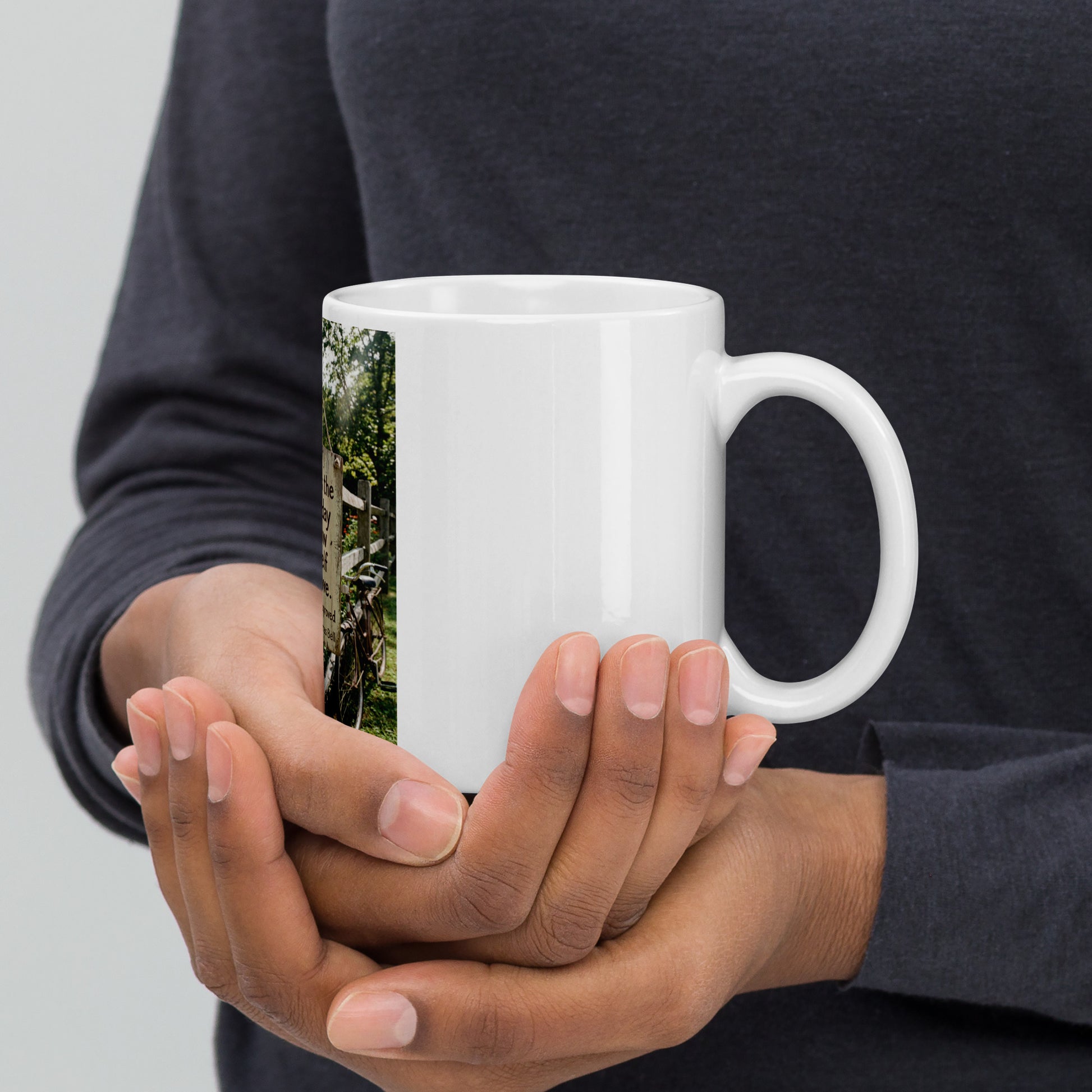 White glossy mug held with both hands, front graphic visible on sleeve
