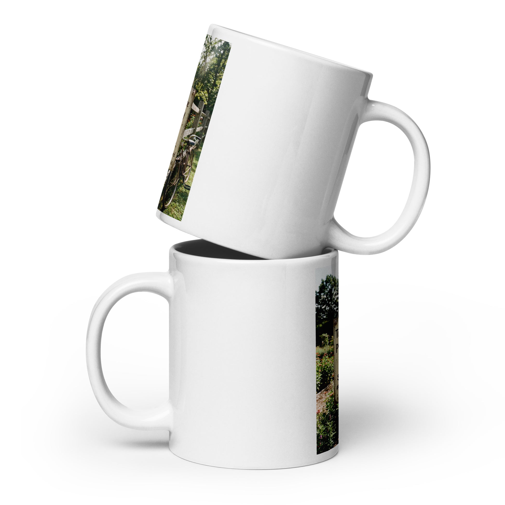 White glossy ceramic mugs stacked, showing green vertical print and handle.