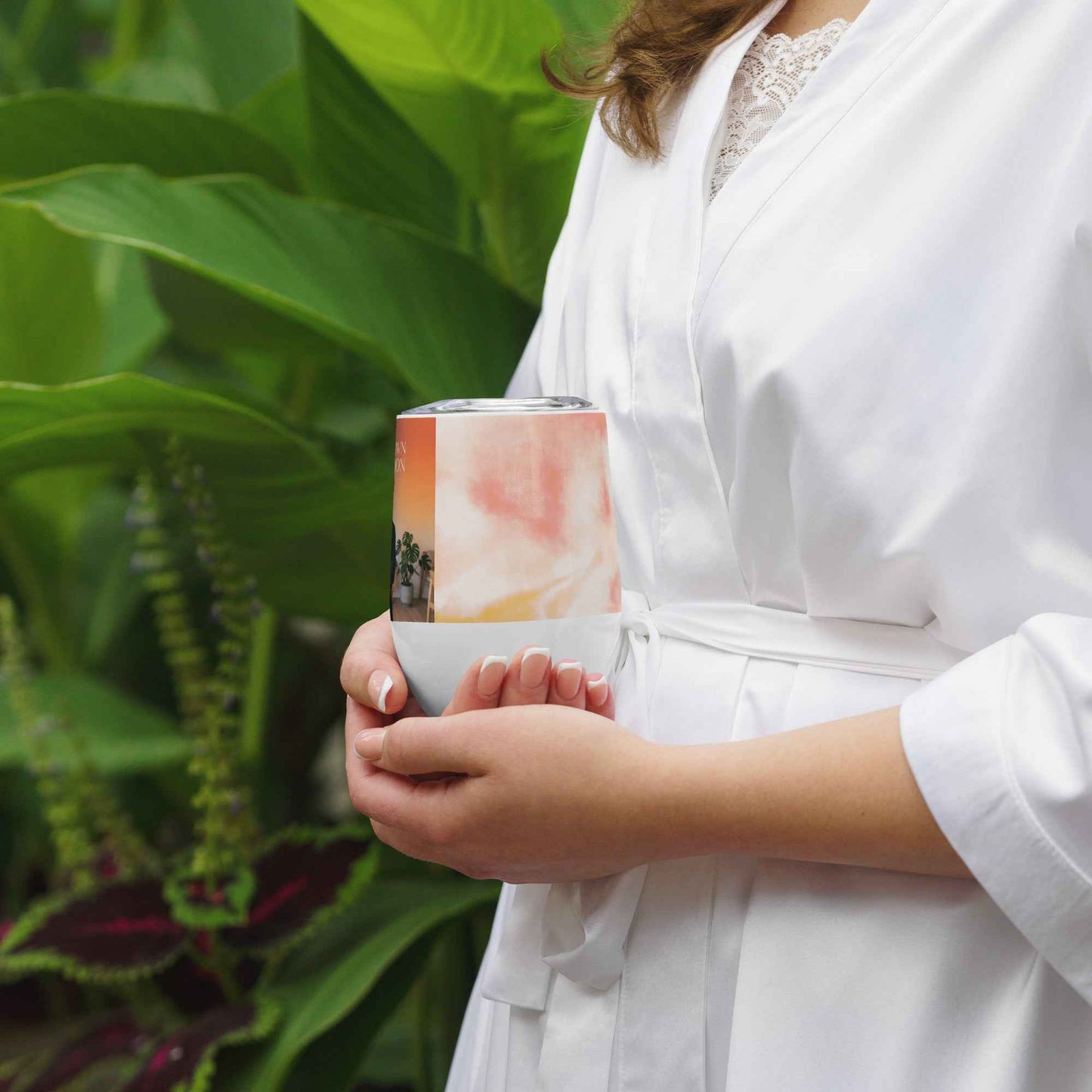 Wine tumbler with printed wrap in peach tones, held in hand
